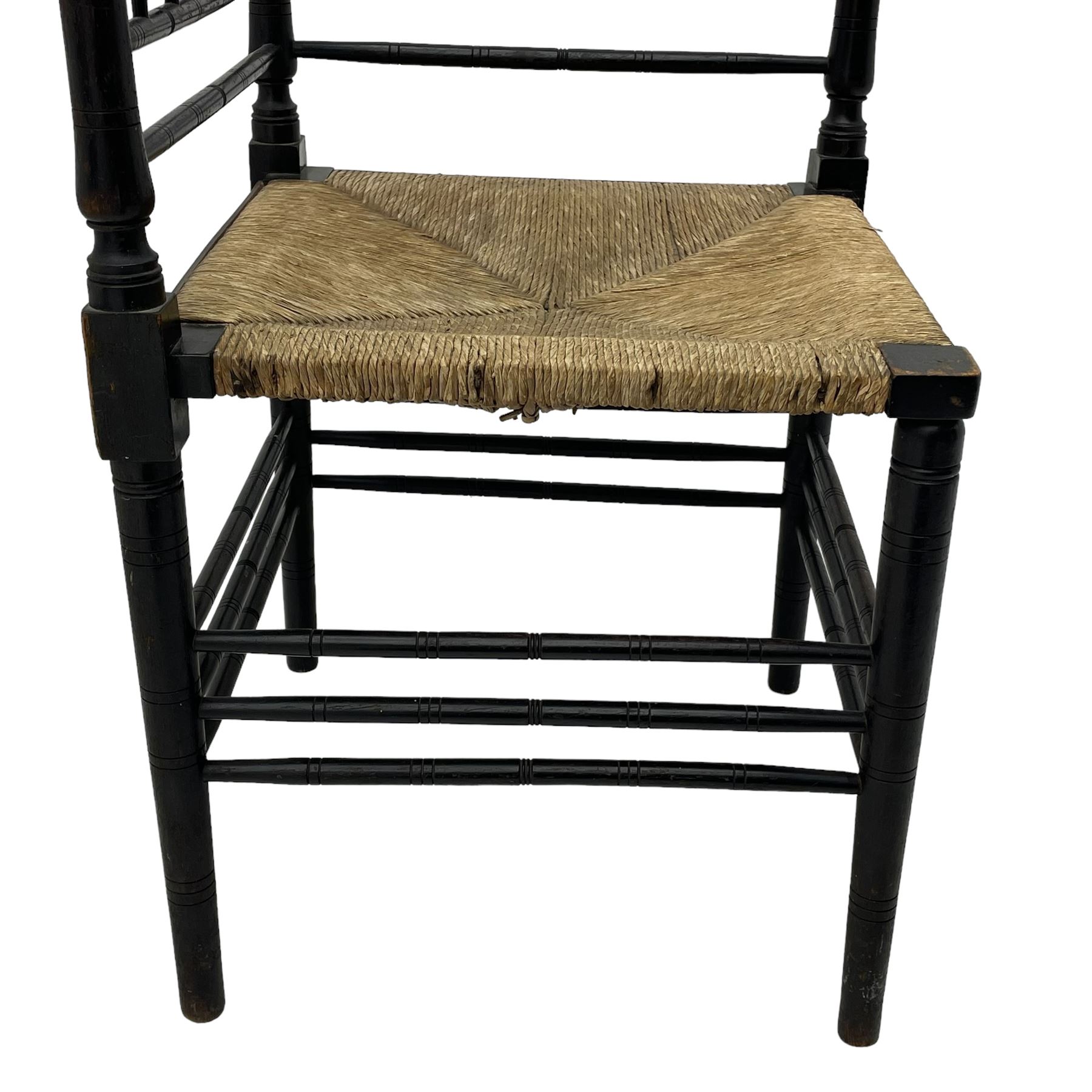 In the manner of William Morris - Arts & Crafts period corner chair, swell turned horizontal rails with balustrade back, rush seat on ring turned supports, black paint finish 