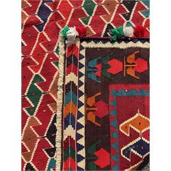 Southwest Persian Qashqai Kilim crimson ground rug, decorated with a repeating geometric pattern of interlocking diamond motifs in red, green, blue, and brown, enclosed by a deep brown border with stylised floral motifs and colourful fringe accents