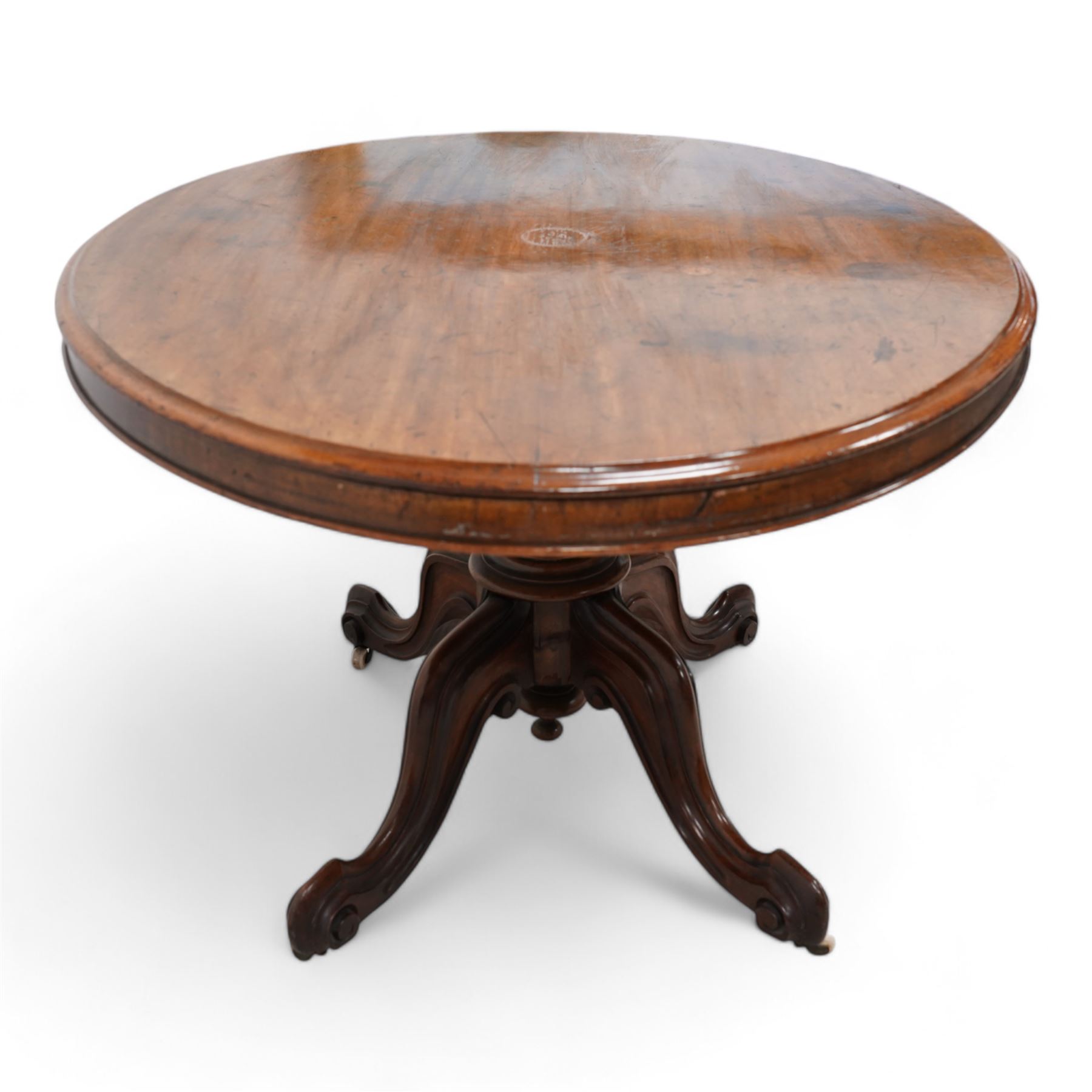 Victorian mahogany loo or centre table, moulded oval tilt-top, turned pedestal on four out splayed carved supports with scrolled terminals, on brass and ceramic castors 