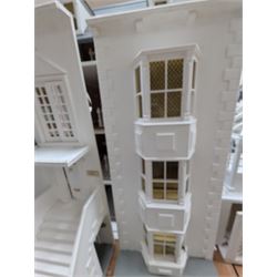 Large three storey modern dolls house, painted white with latticed windows, grey roof and metal fencing, with decorated interior, together with two dolls house garden rooms and two conservatories