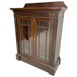 19th century mahogany display cabinet, rectangular top over frieze decorated with Vitruvian scroll mount, enclosed by two astragal glazed doors, the upright rails decorated with trailing bellflowers, on moulded plinth