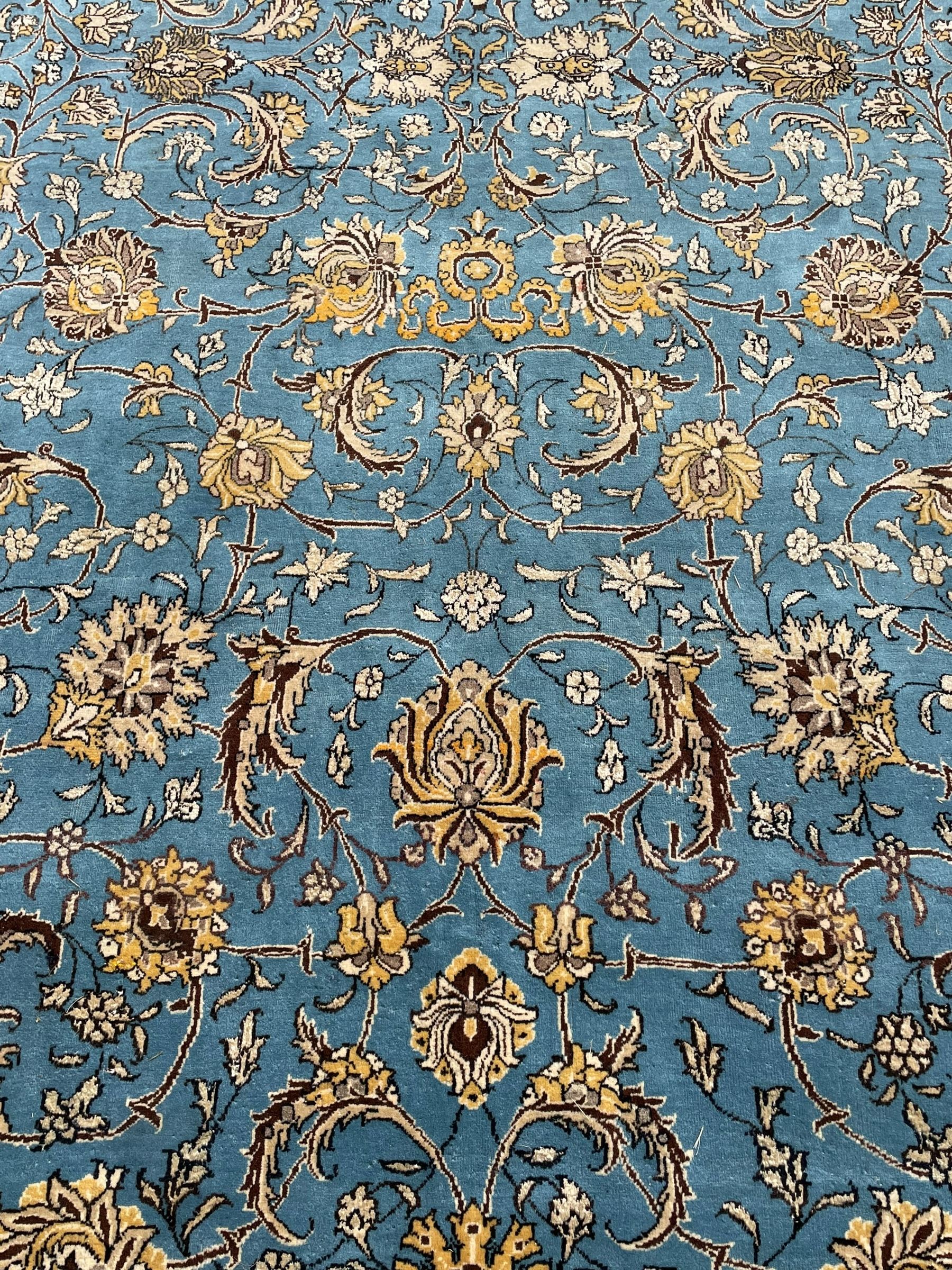 Persian Nain blue ground rug, overall arabesque design, the busy field decorated with interlacing branches and palmettes, indigo ground border with panels decorated with knots and lotus flower motifs, surrounded by trailing branches and flower heads, within guard stripes