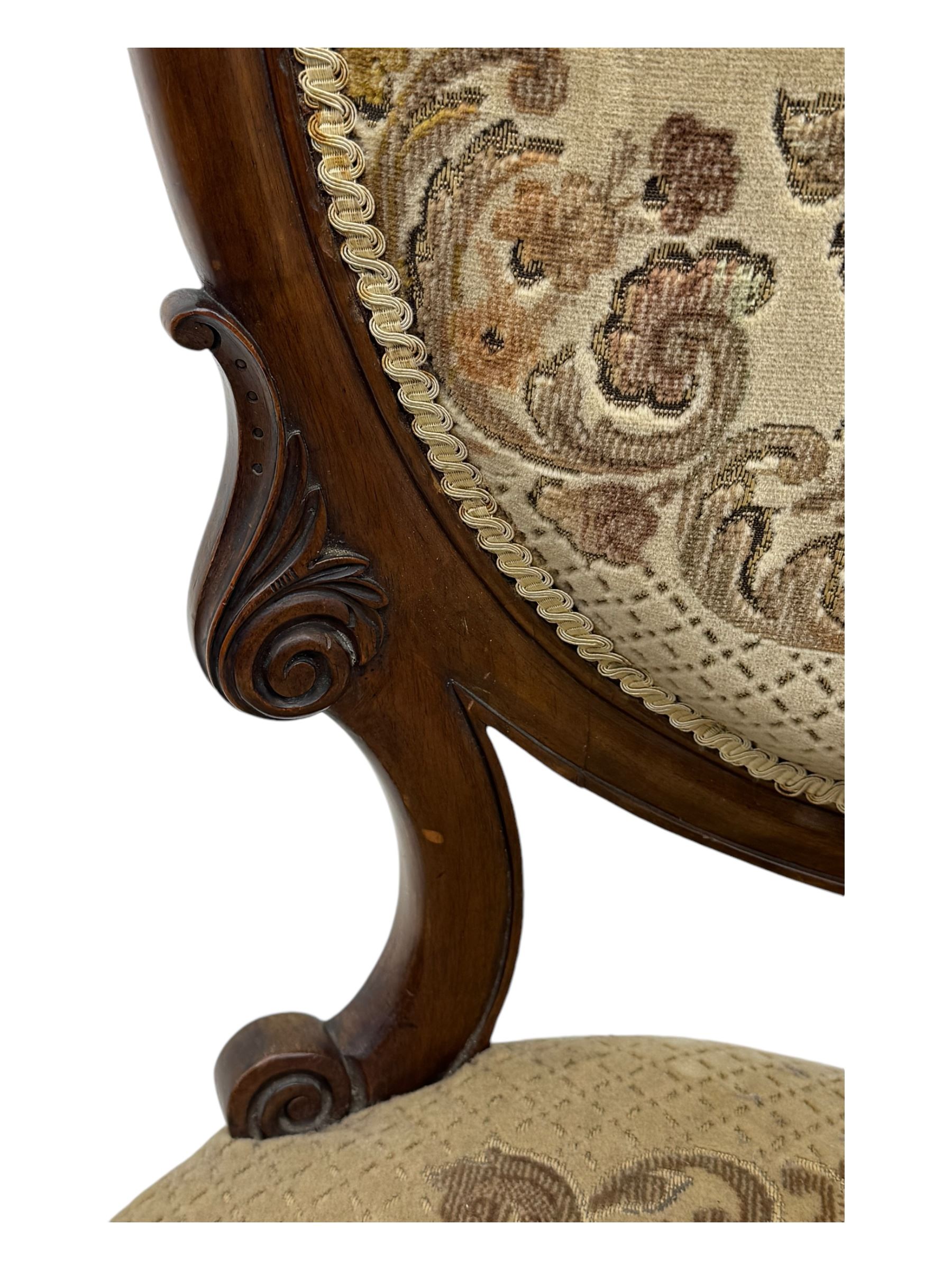 Pair of Victorian walnut lady's and gentleman's drawing room chairs, arched cresting rail carved with cartouche and extending foliage, upholstered in floral pattern fabric, on foliate carved cabriole feet