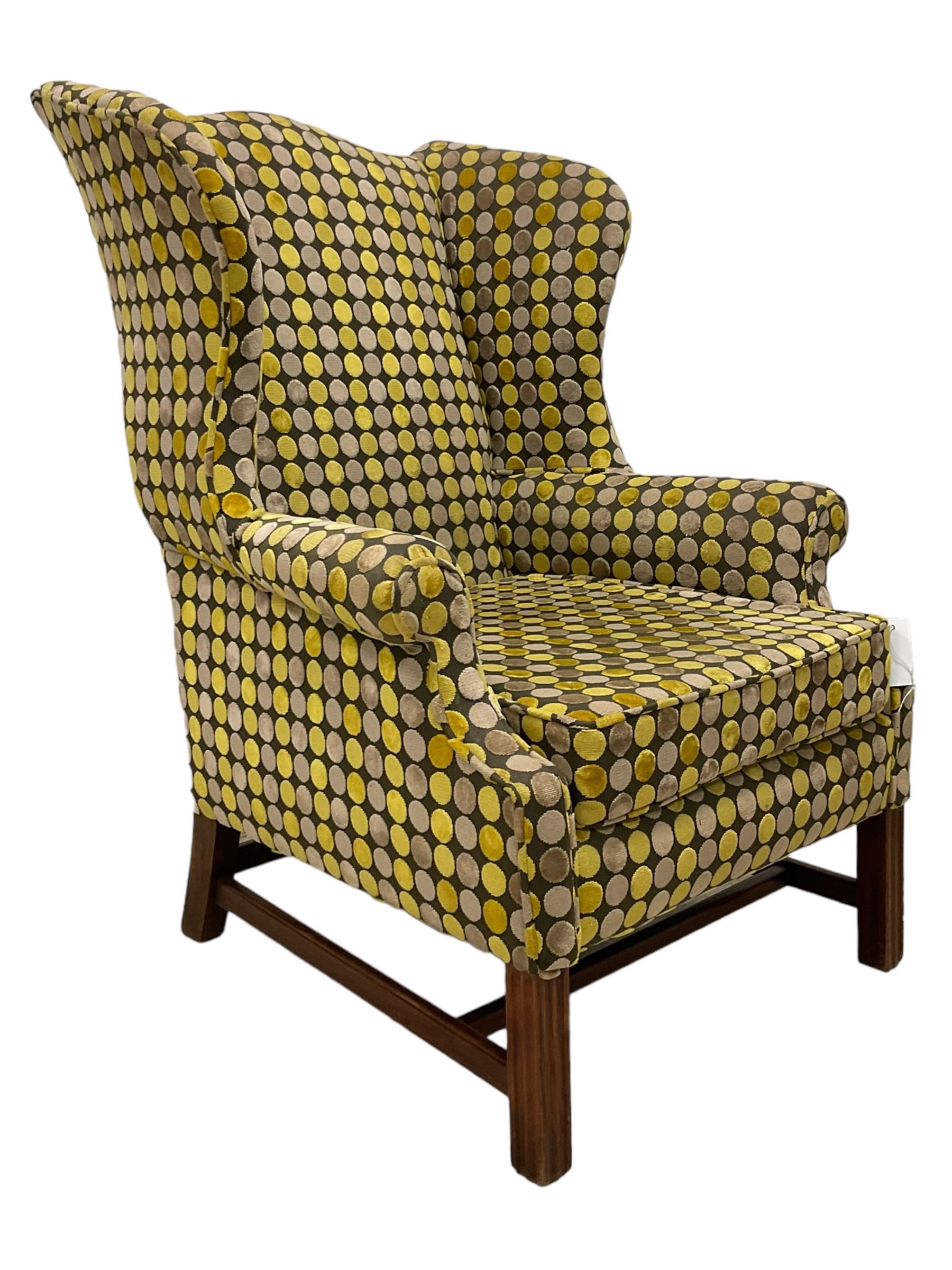 Georgian design mahogany framed wingback armchair, upholstered in spotted fabric in shades of grey and green, on moulded square supports united by stretchers 