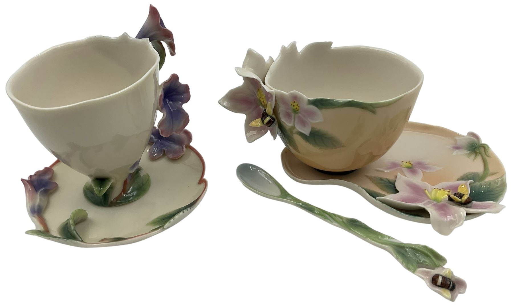 Two Franz teacups and saucers, decorated with flowers, one with matching teaspoon