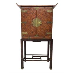 Chinese design bamboo and wood altar cabinet on stand, parquetry lattice-work bamboo, two doors with engraved metal fixtures enclosing drawers and shelf, fitted with slide, the stand pm square supports joined by a series of geometric stretchers