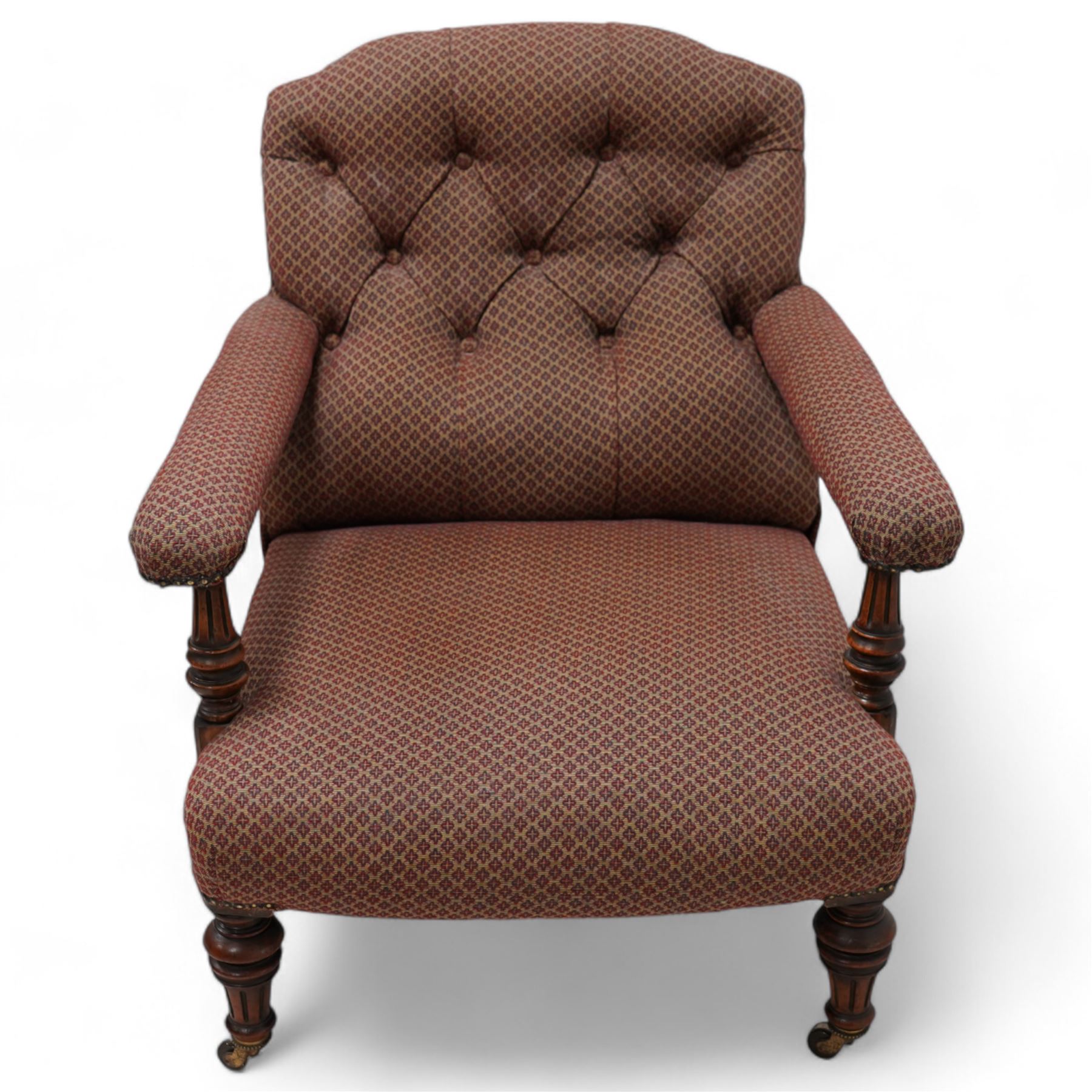 Late 19th century drawing room walnut framed open armchair, arched back over fluted and turned arm terminals and deep sprung seat, upholstered in buttoned maroon patterned fabric with stud detail on turned and fluted supports with castors