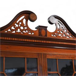 Early 19th century mahogany and satinwood bookcase on stand, scrolled swan neck pediment with pierced panels, satinwood frieze over two astragal glazed doors enclosing adjustable shelves, fitted with two drawers, the stand with rectangular satinwood banded top over frieze inlaid with central shell panel and extending bell flower festoons, on square tapering supports united by undertier with raised gallery 