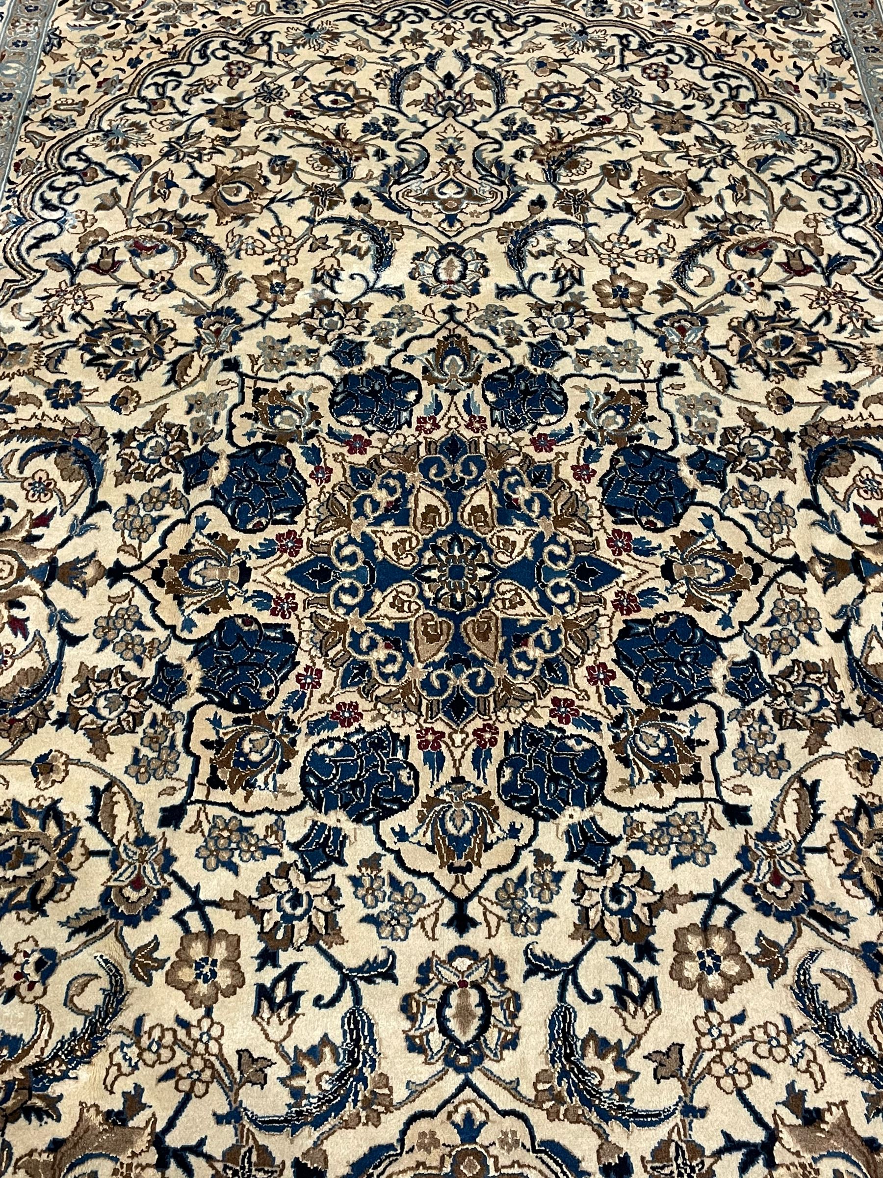 Persian ivory ground carpet, overall floral pattern with central rosette medallion, the field decorated with interlaced leafy branches and stylised plant motifs, guarded repeating border with repeating design