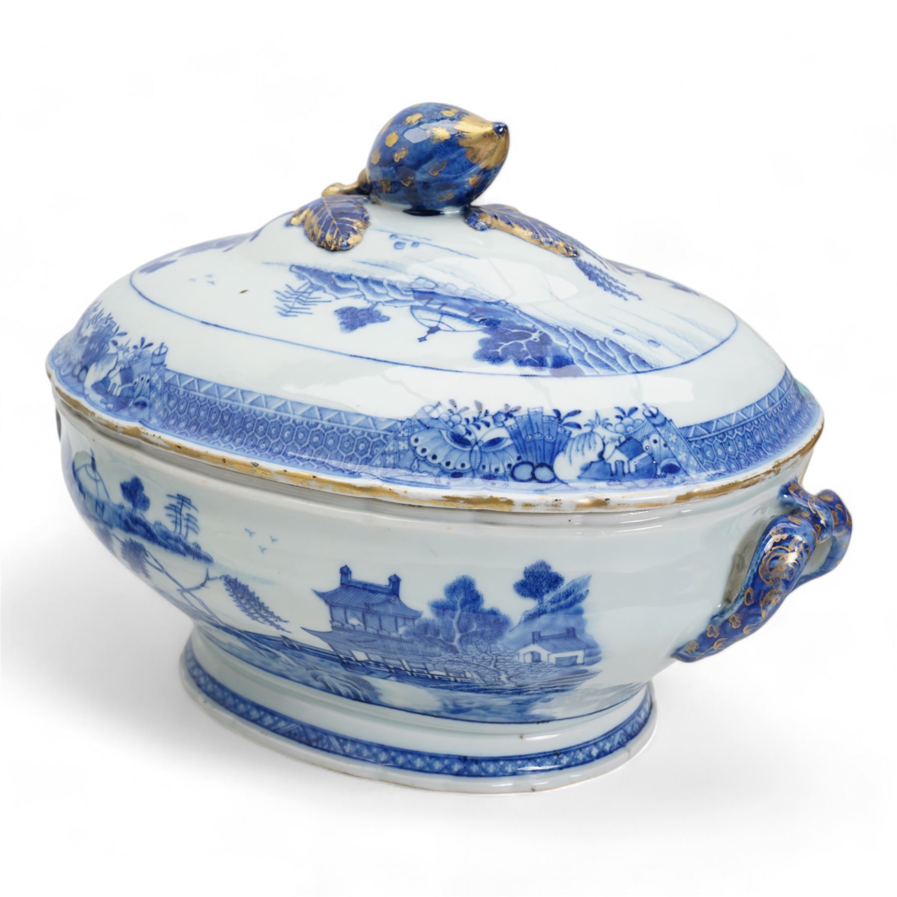 Pair of 18th century Chinese Export blue and white parcel gilt lidded tureens, each of twin handled oval form, decorated with buildings and landscape scenes within geometric and cell borders, with fruit finials, L33cm x H26cm approx.