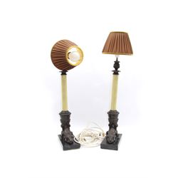 Pair of bronze effect brass table lamps, modelled as cornucopia issuing from rams heads, leading to a crackle effect column supporting pleated fabric shades, the whole upon black stone plinths, overall H67cm 