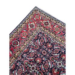 Persian Farahan indigo ground rug, the field decorated with large repeating floral herati motifs, crimson ground border decorated with palmettes and trailing leafy branch, within guard stripes 