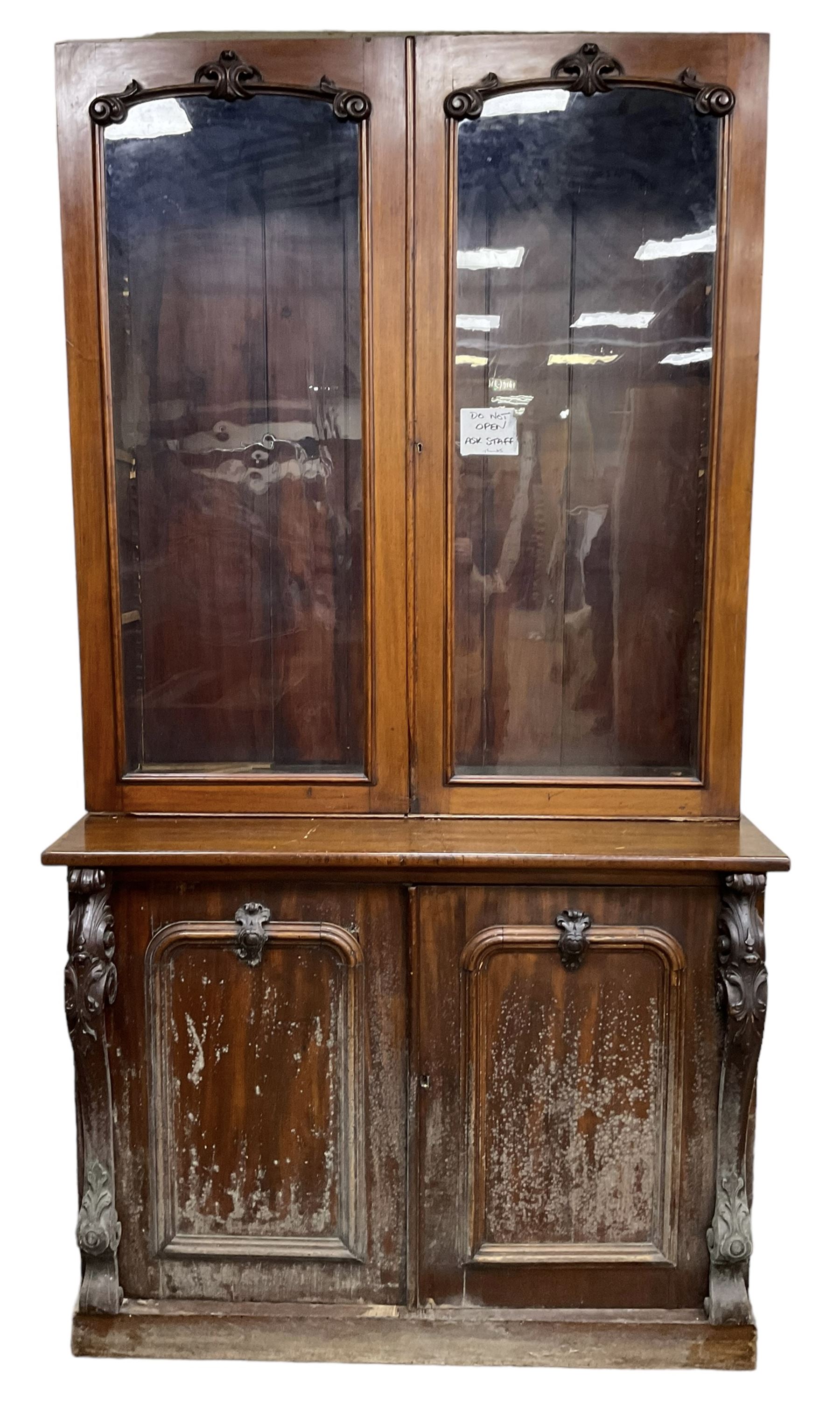 Victorian mahogany bookcase on cupboard, enclosed by two glazed doors, the base enclosed by two panelled doors flanked by acanthus carved upright pilasters, on plinth base