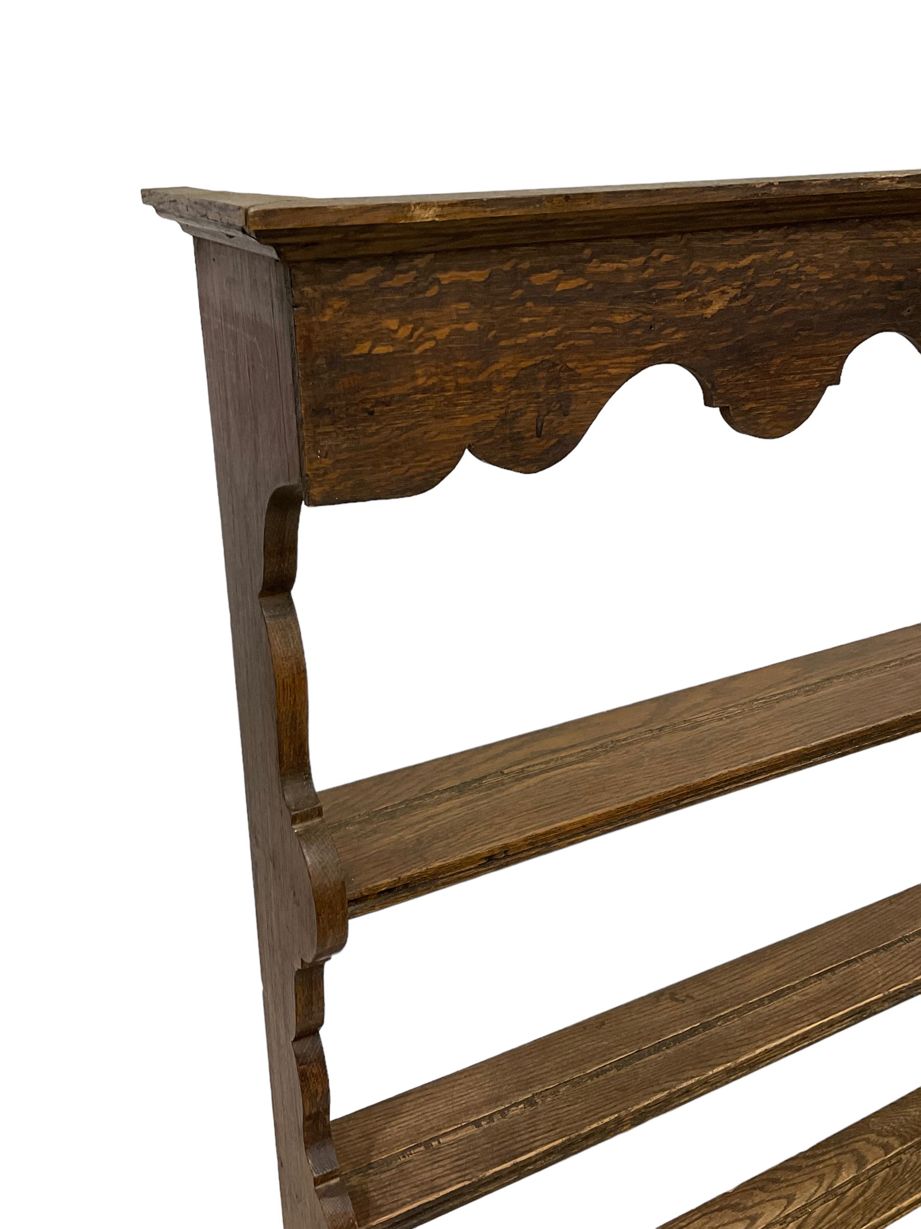 Early 20th century oak wall hanging Delph rack, applied moulded cornice over shaped frieze, three-tiers supports by shaped end supports