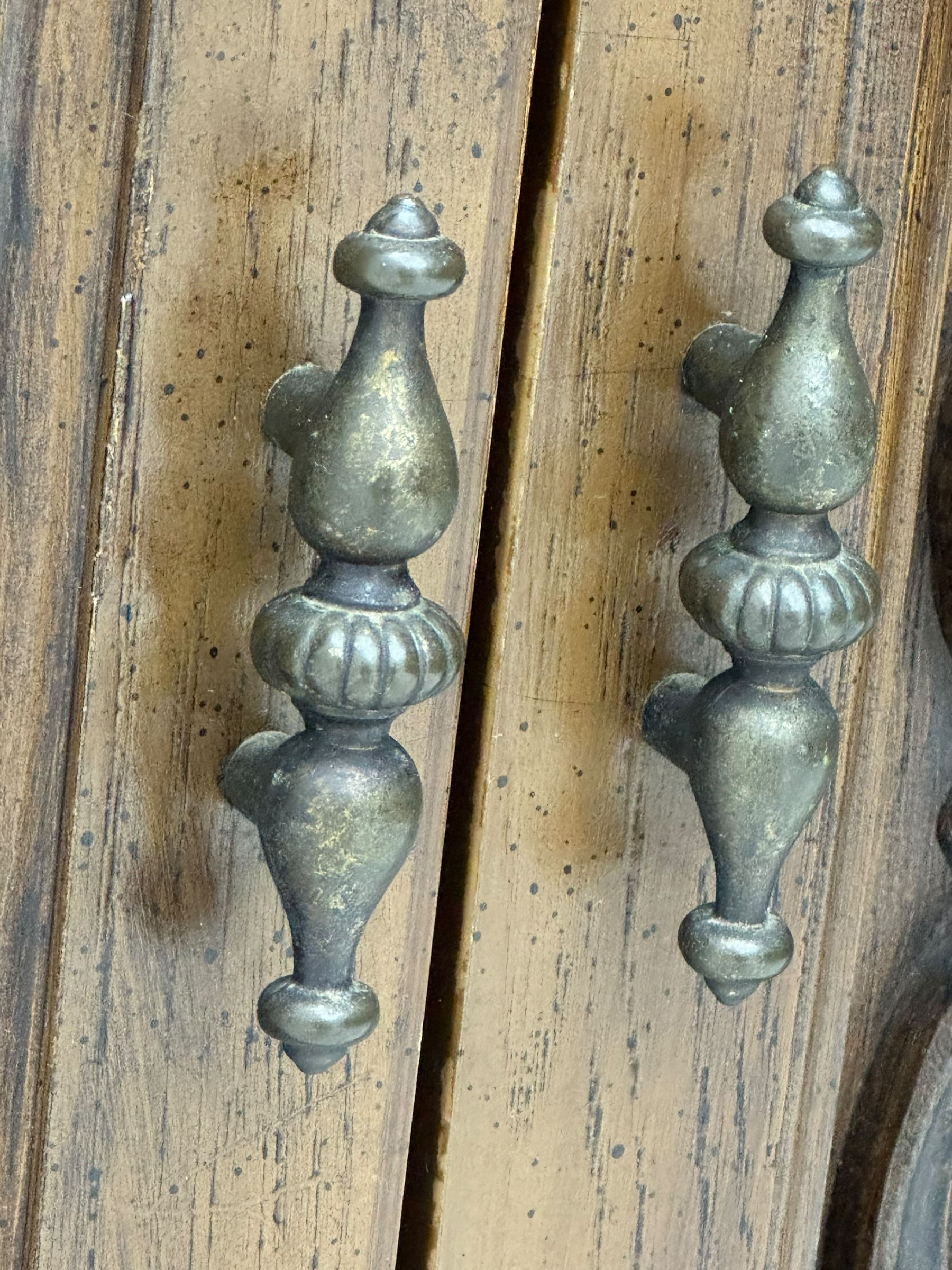 Mid 20th century oak bookcase cupboard, projecting cornice over three open shelves with subdivided sections and latticework uprights, two doors to the base with floral and scrollwork carvings and central brass handles, resting on a moulded plinth base