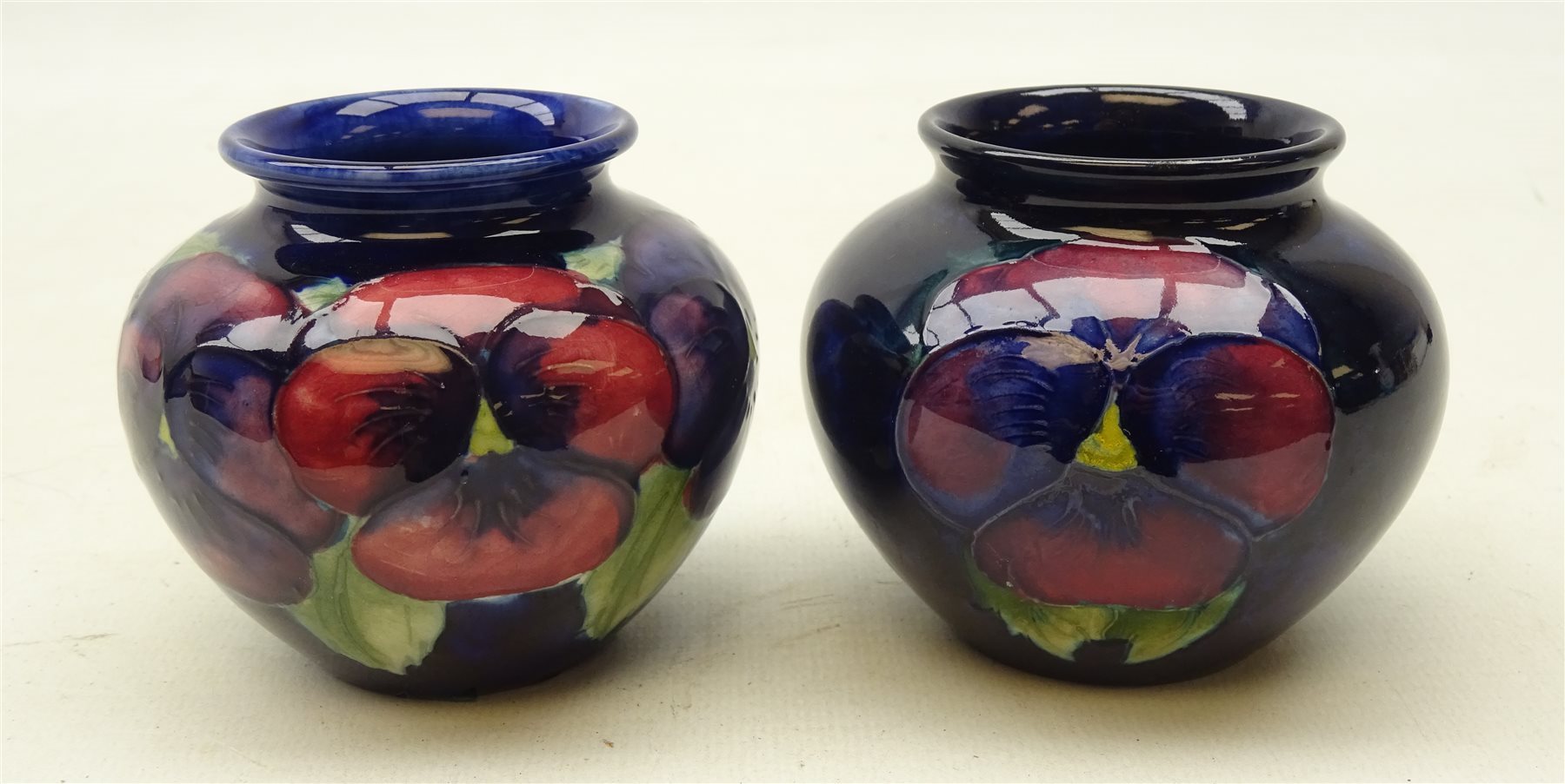 Two Moorcroft Pansy pattern baluster vases on blue ground, H7cm (2)