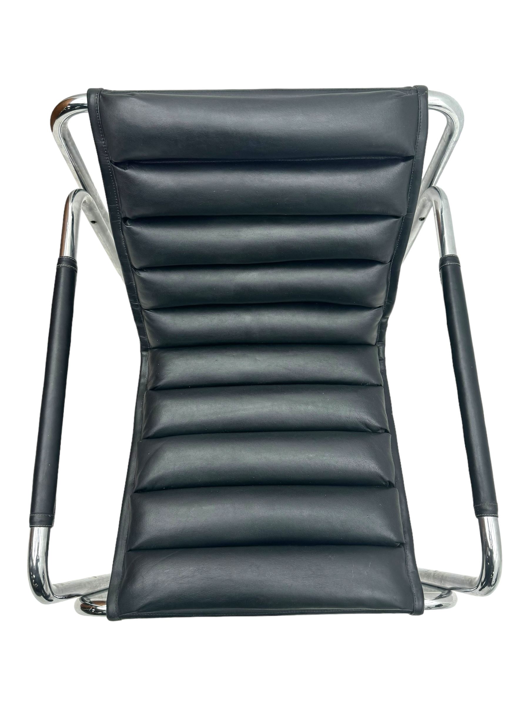 Baroumand Designs - pair of mid 20th century modernist armchairs, slung black leather seat with horizontal channel tufting, tubular chrome frame with curved arms, raised on tubular supports