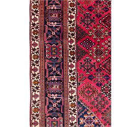 Persian Joshaghan red ground rug, the medallion, field and spandrels decorated with Pitrak and tree of life motifs, the border with repeating design decorated with stylised plant motifs, within guard stripes