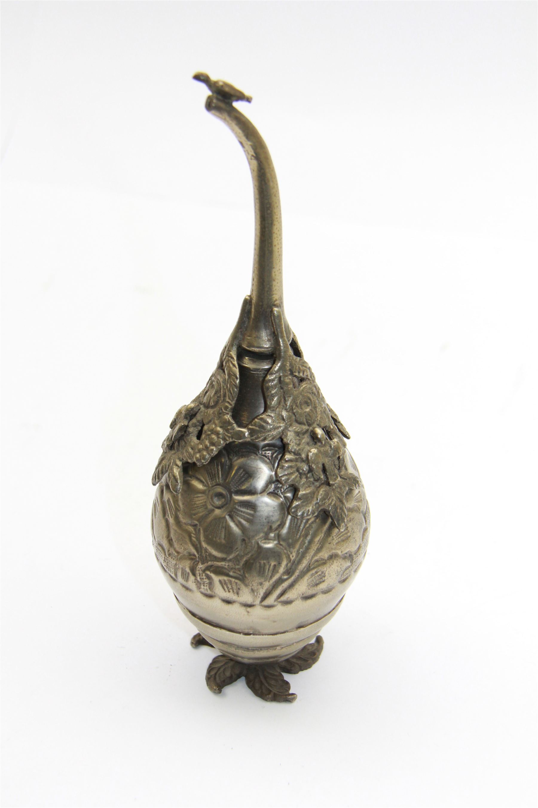 Egyptian white metal rosewater sprinkler, the pear shaped body embossed with flowers, the screw top with applied rose and bird decoration, upon foliate base, H20cm