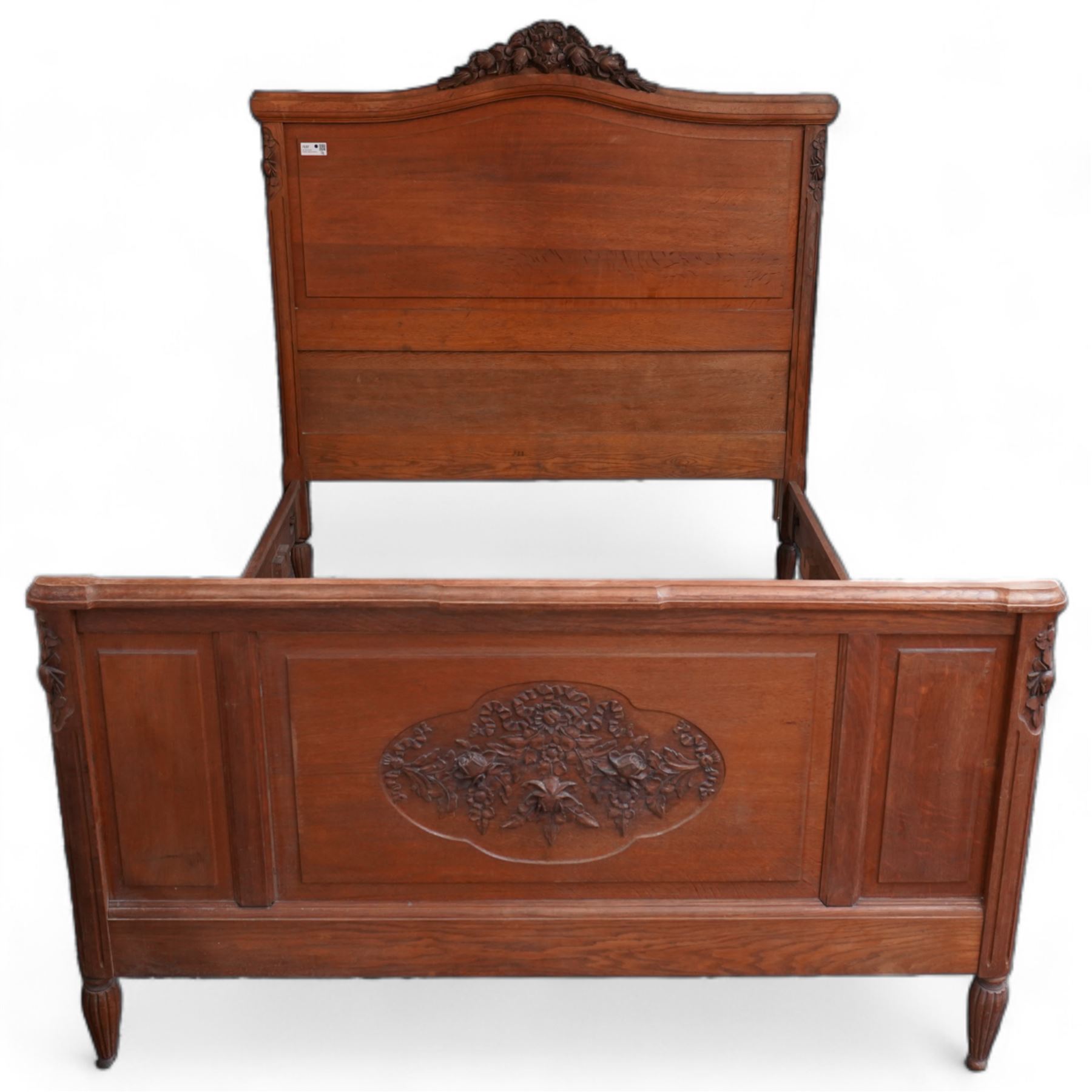 Late 19th century French oak double bedstead, headboard with shaped rail and carved pediment, carved footboard