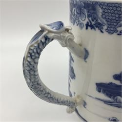 Two large 18th century Chinese blue and white tankards, each of cylindrical form, the first example with foliate mounted strap handle, the body painted with a shaped panel depicting a riverside landscape with pagodas and pine trees, against a textured ground decorated with floral sprays, H15cm D12cm, the second with serpent handle, the body painted with a similar riverside landscape, H14cm D12cm