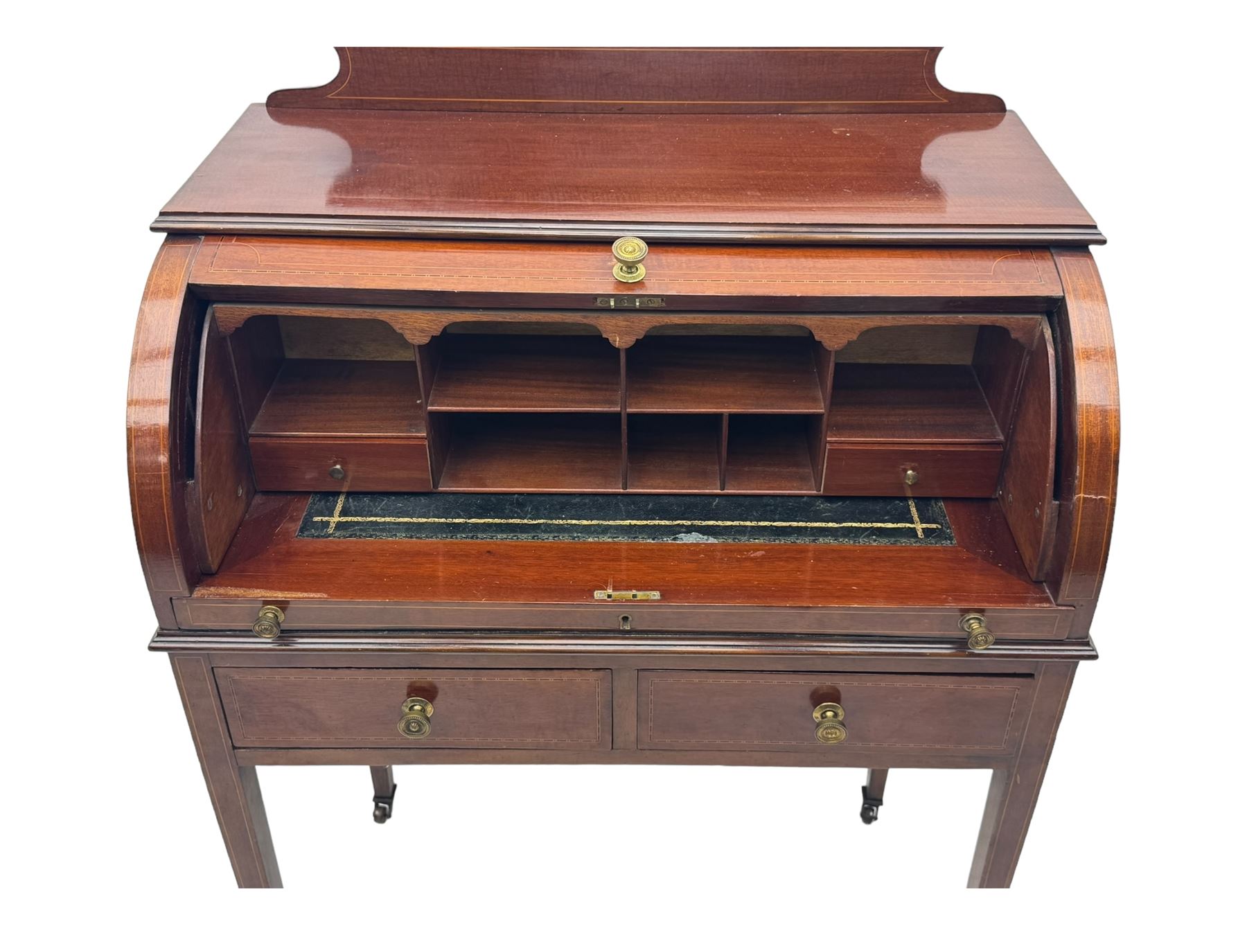 Edwardian inlaid mahogany roll-top desk, cylindrical lid enclosing fitted interior with pigeonholes, drawers and retractable writing surface, over two drawers with brass pull handles, on tapered supports with brass and ceramic castors