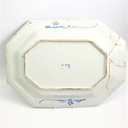 Two English Delft dishes, of canted rectangular form, painted with a fence, flowering plants and bamboo, within a scroll border, one marked F beneath, 49.5cm x 37.5cm max (2)