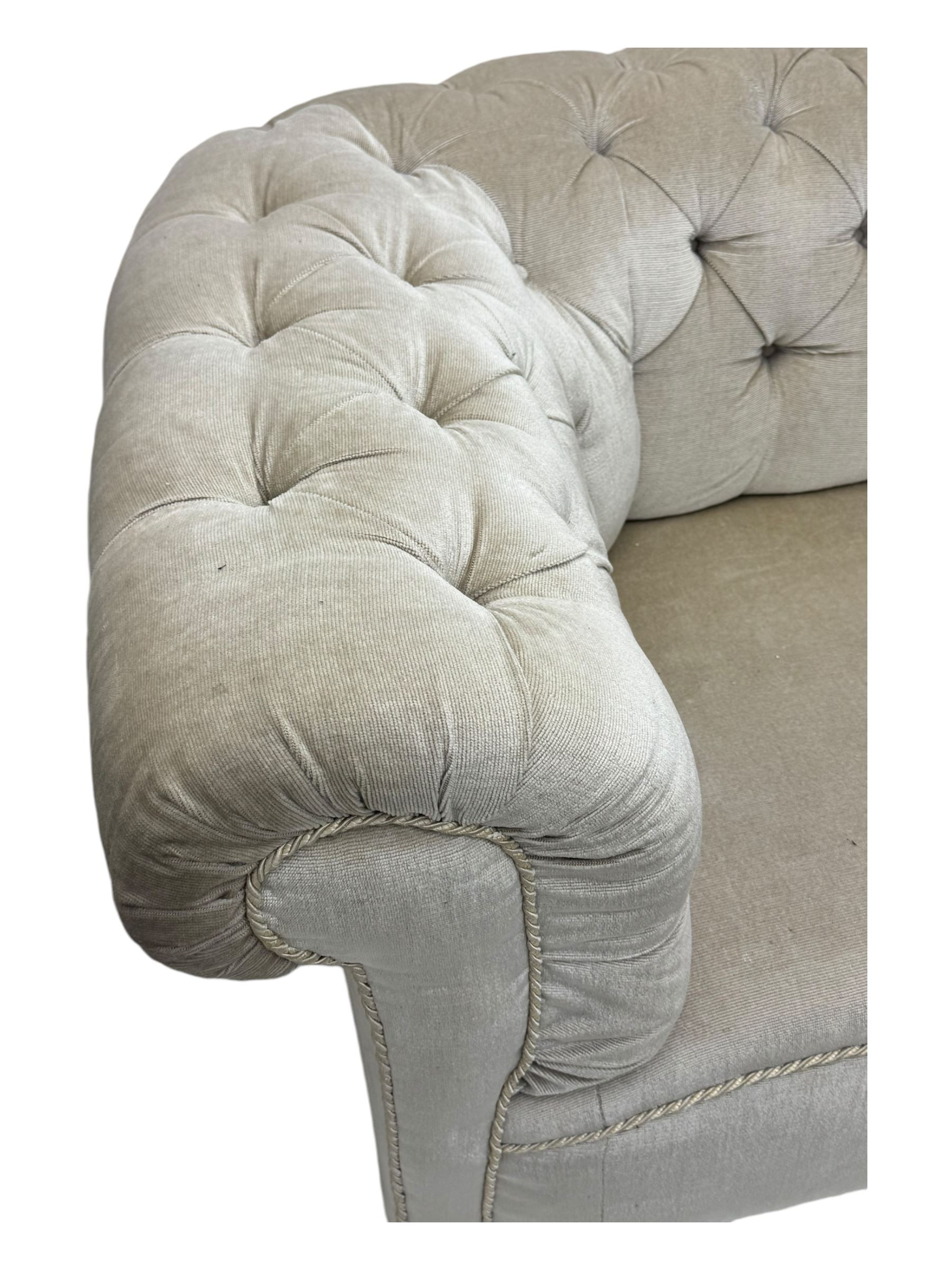 Chesterfield shaped button-tufted sofa, upholstered in pale beige velvet fabric with rolled arms, decorative rope trim and ruched detailing