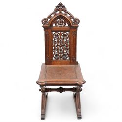 In the manner of Augustus Pugin - 19th century Gothic Revival oak hall chair, shaped pediment carved and pierced with foliate decoration, panelled back pierced with floral quatrefoil and scrolled decoration, panelled seat with moulded seat frame with projecting curved corners, on moulded X-framed supports united by turned and faceted stretcher, on sledge feet 