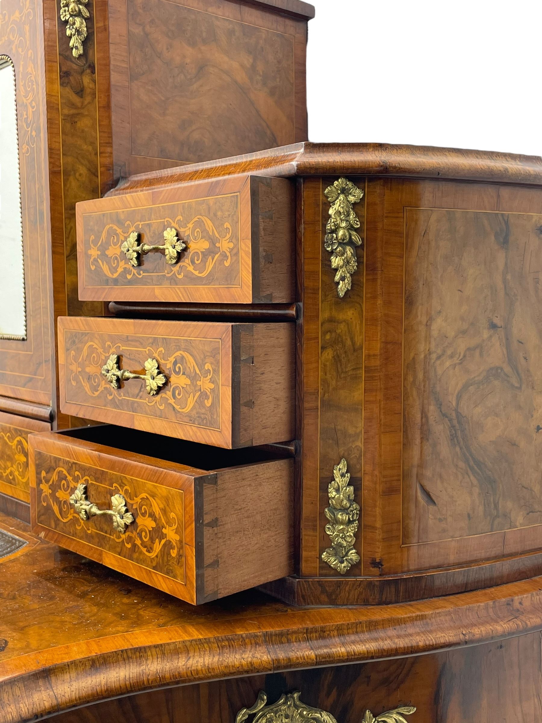 19th century French figured walnut Bonheur de Jour or writing desk, the upper section with brass gallery over mirror glazed cupboard and a combination of drawers, shaped and moulded top with leather inset and satinwood band, fitted with single drawer, on cabriole supports, inlaid throughout with scrolling foliate decoration in boxwood, ornate cast brass mounts 