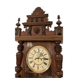 Gustav Becker -  German weight-driven 8-day wall clock in a walnut and ebonised case with a carved pediment and finials, fully glazed case door with visible pendulum and two brass cased weights, two  part dial with seconds hand, Roman numerals and pierced steel hands, rack striking movement with a deadbeat escapement.