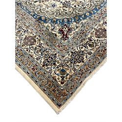 Persian Nain ivory ground carpet, the field decorated all over with leafy branches and stylised flower head motifs, blue ground central medallion and matching spandrels decorated with trailing foliate pattern, repeating guarded border with overall floral design