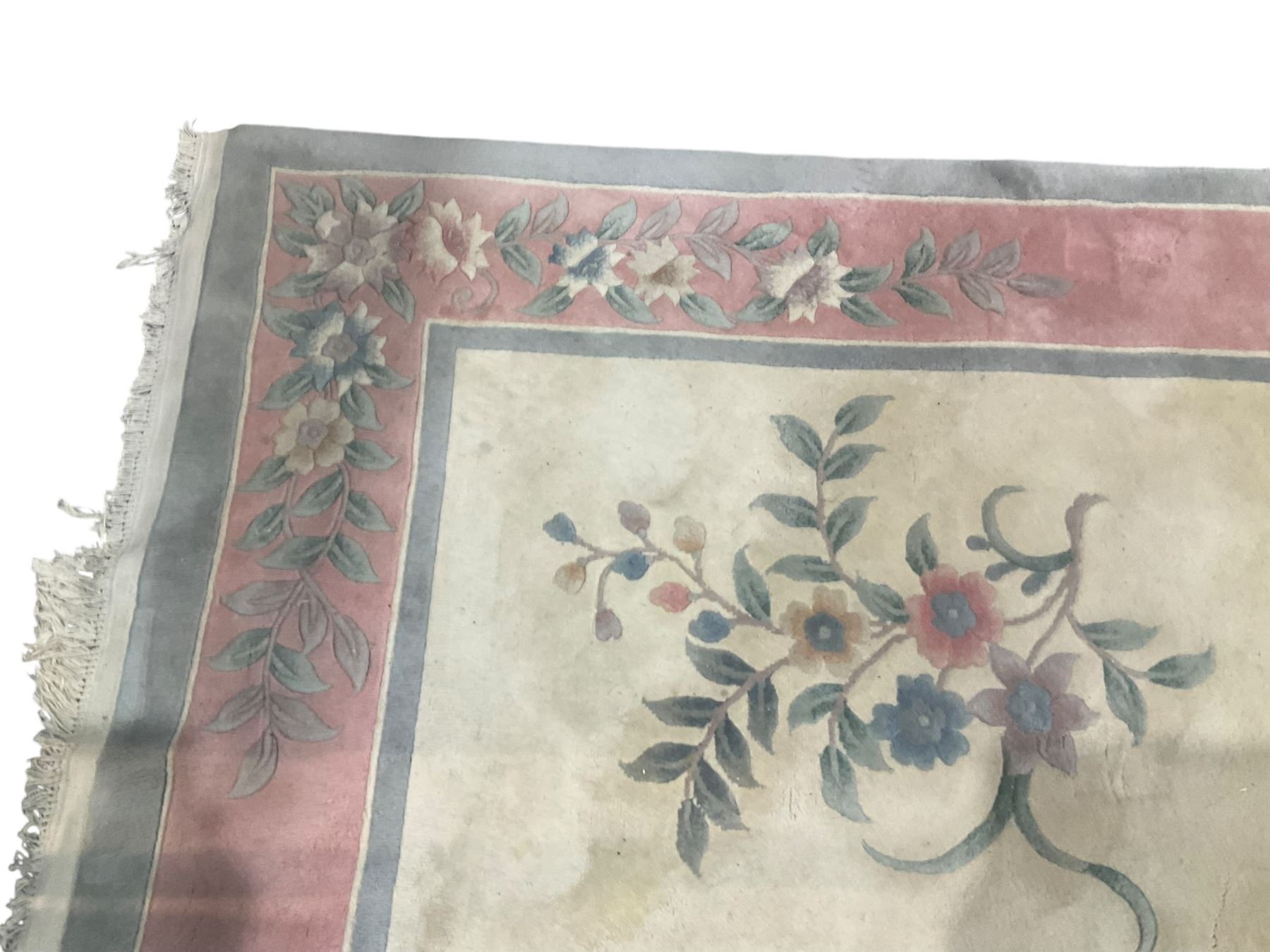 Chinese ivory ground washed woollen carpet, the field decorated with five large floral motifs with extending leafage, the wide rose guard band decorated with further floral patterns