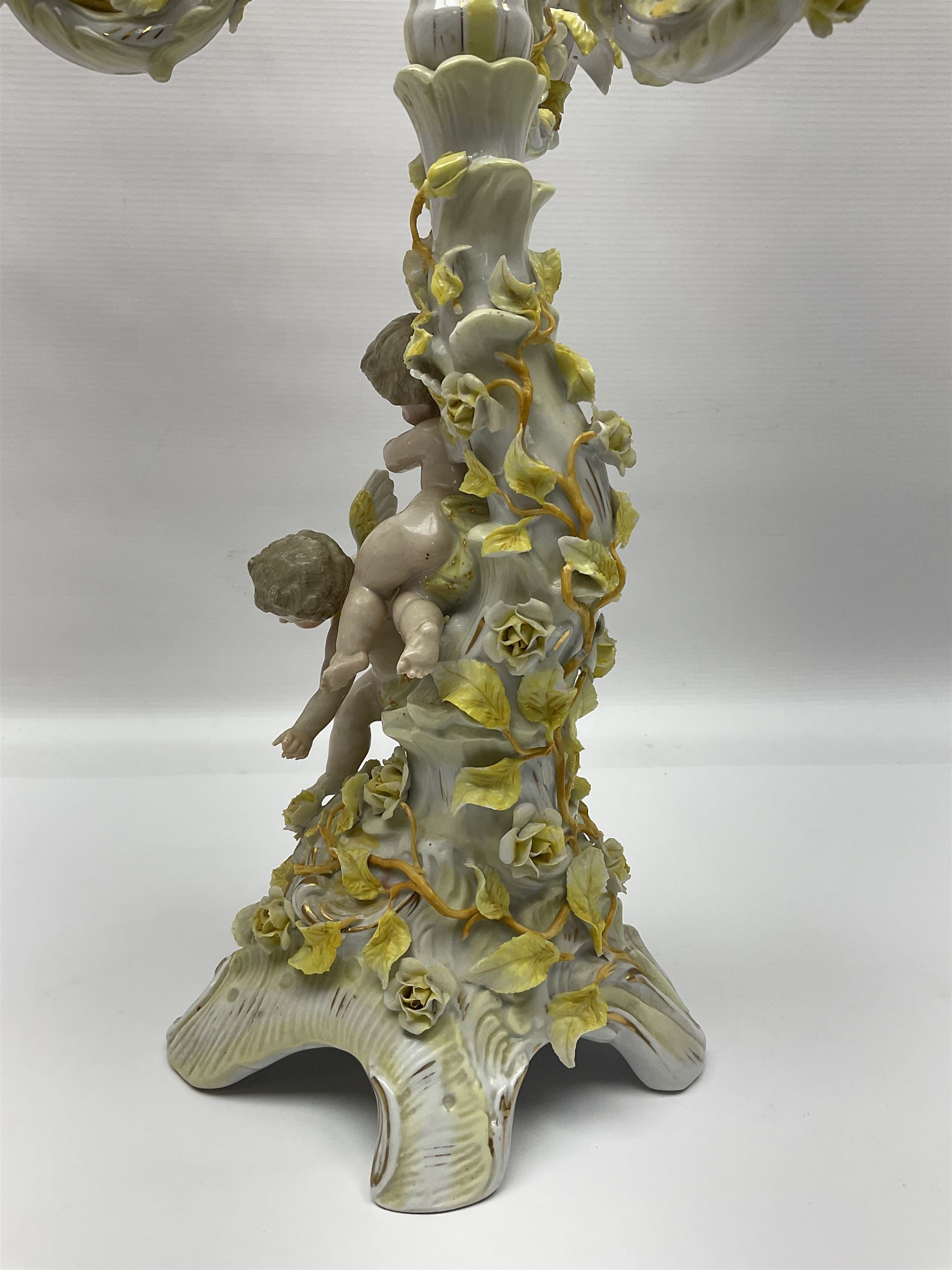 Dresden style candelabra, the central stem bordered by three branches, decorated with cherubs and yellow roses, H48cm