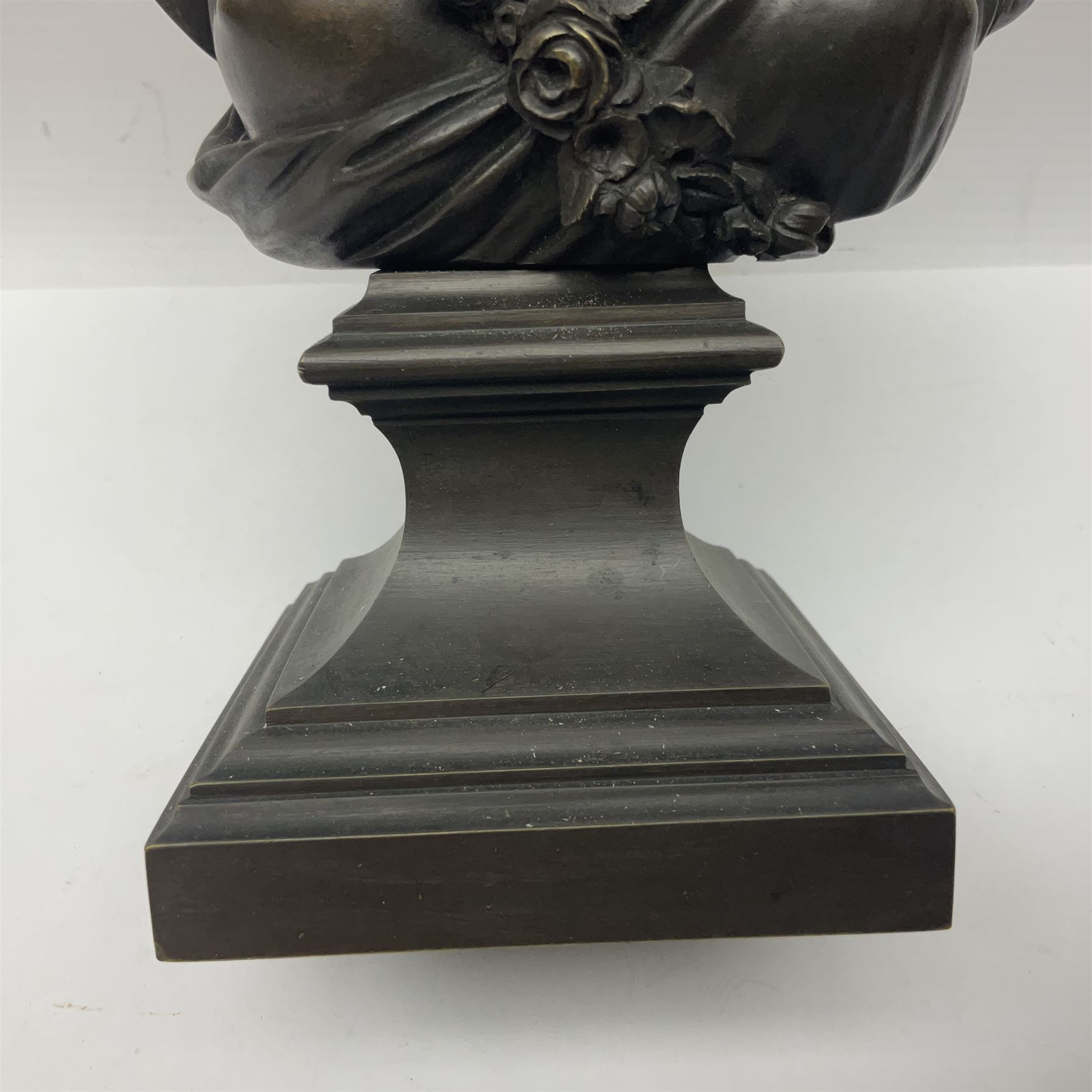 Bronze bust, modelled as a maiden in classical drapery and adorned with floral swags, upon a fluted socle base, overall H23.5cm