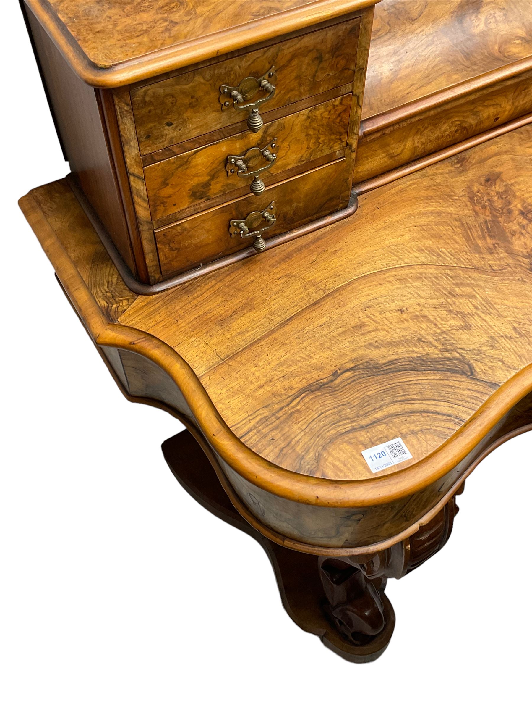 19th century figured walnut dressing table, the raised bevelled mirror back in carved foliage frame with scrolled terminals, fitted with central hinged compartment flanked by small trinket drawers, serpentine moulded top over single frieze drawer, on cabriole supports united by a platform base