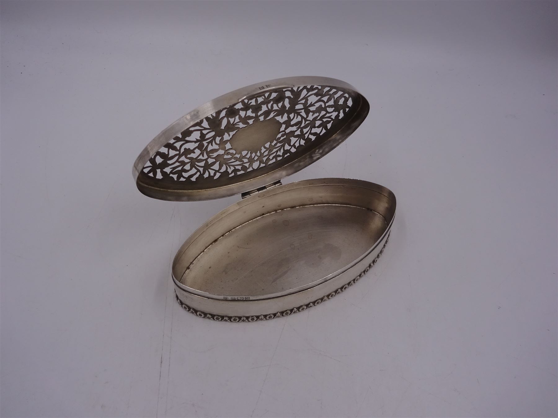 Edwardian silver trinket box, of navette form, the hinged cover with pierced floral and foliate decoration, and blank cartouche, hallmarked George Nathan & Ridley Hayes, Birmingham 1915 and stamped to base Pearce & Sons Silversmiths Leeds & York, W15.5cm, H3.5cm, 