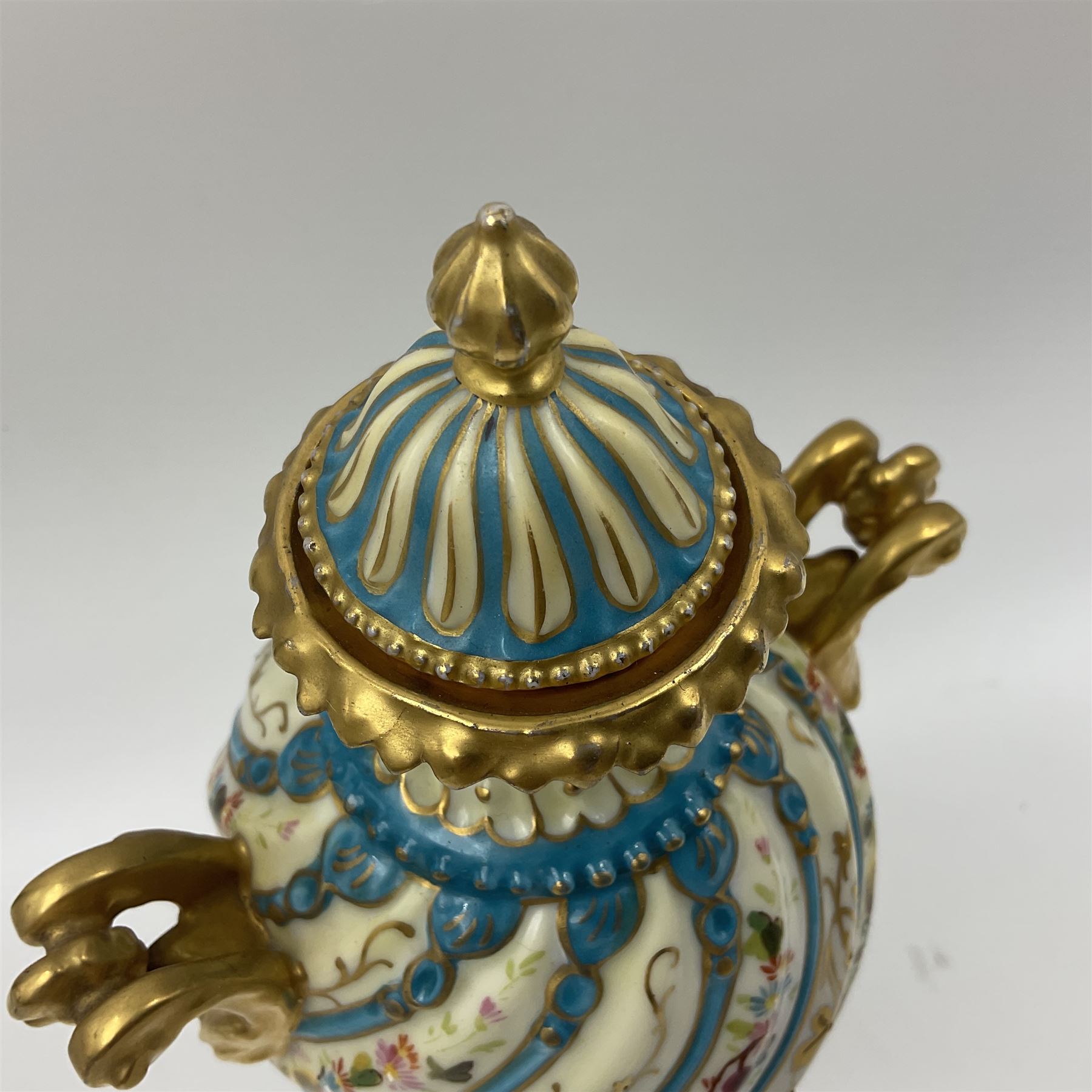 Pair of late 19th/early 20th century Sevres style vases and covers, of baluster form with gilt scroll handles and domed covers, the wrythen fluted bodies decorated with alternating bands of painted fruit and flowers and gilt vines, upon a white and celeste blue ground, with printed and impressed marks beneath, H22.5cm 