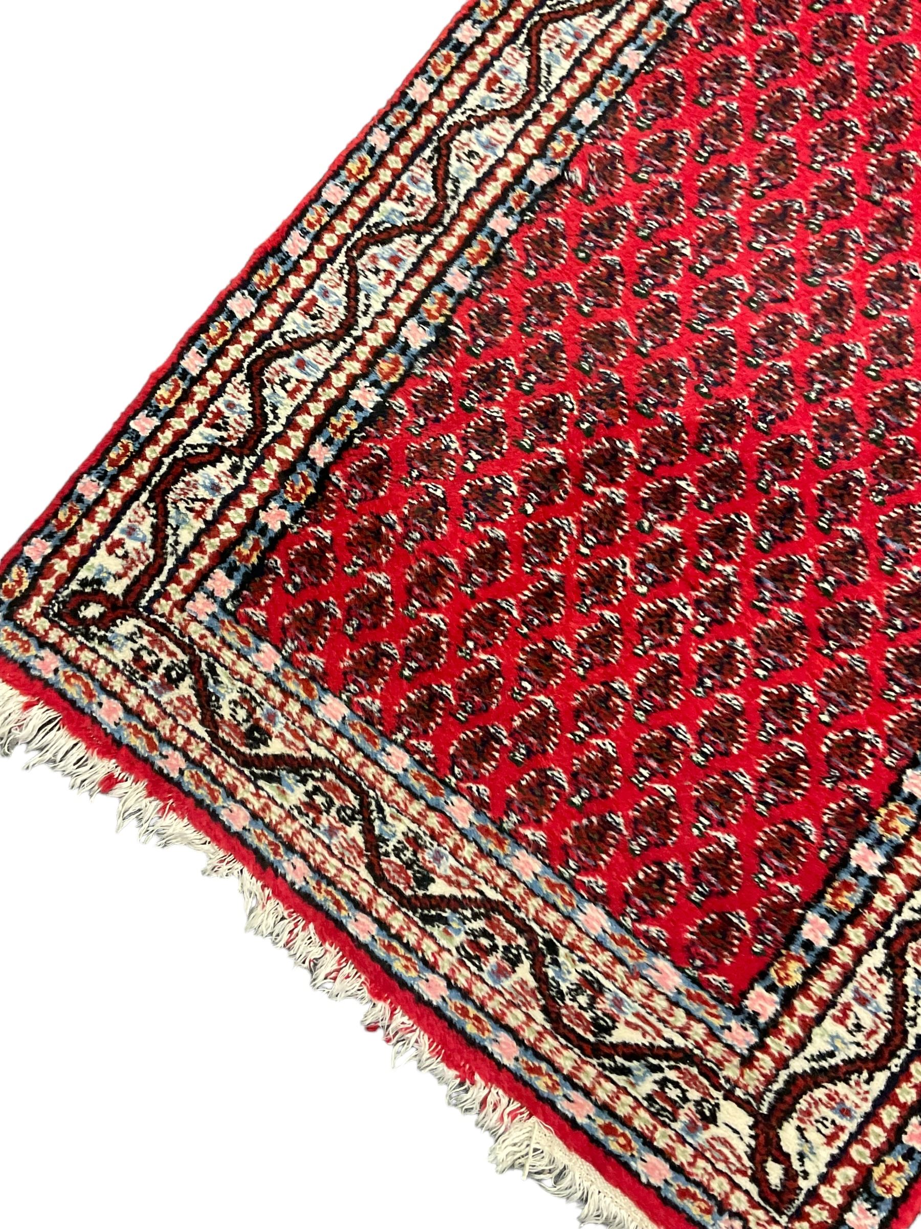 Persian Mahal red ground rug, central floral design pole medallion on a field decorated with flowerheads and foliage, the border decorated with trailing leafy branch and flowerheads 