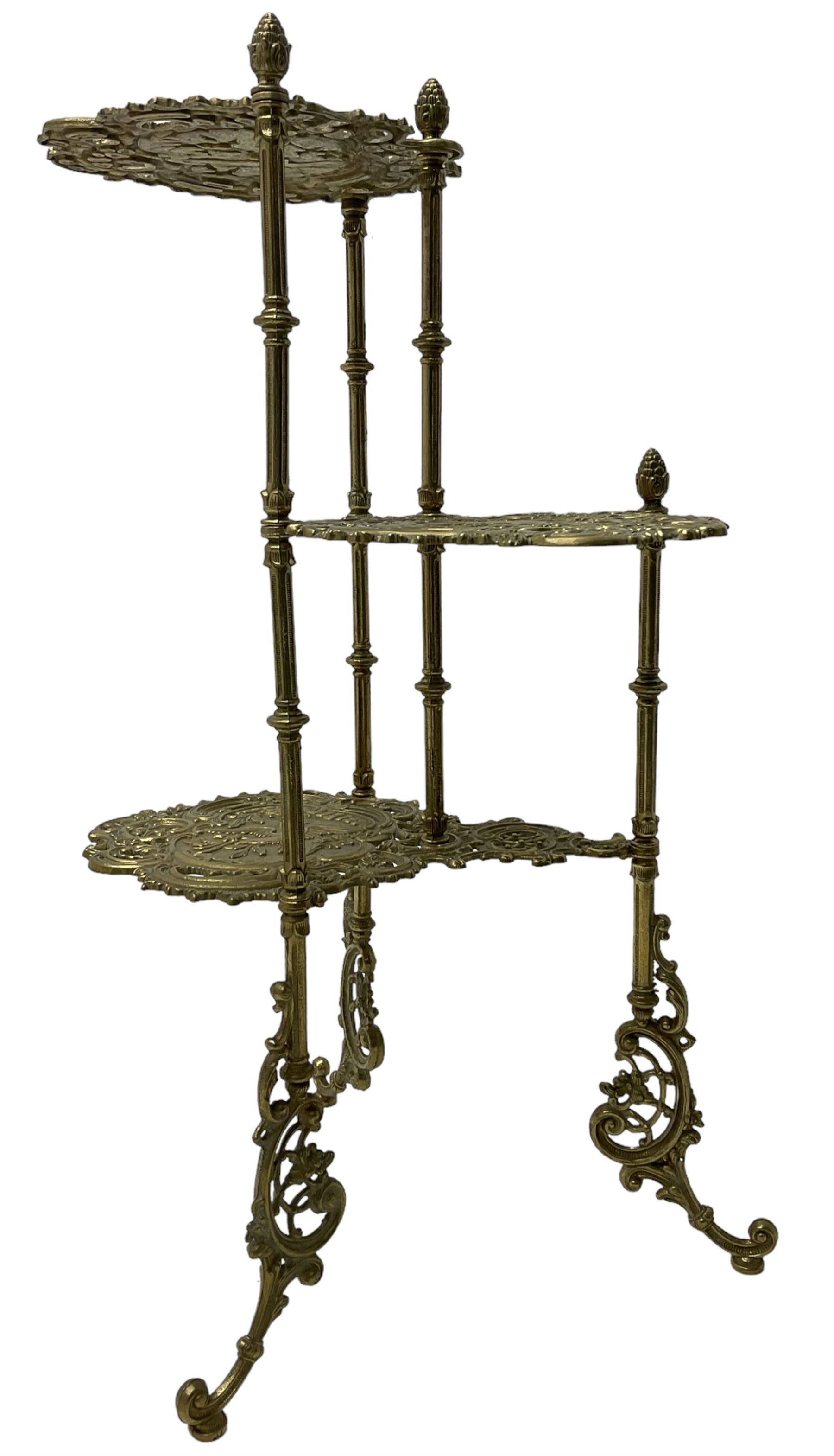 Cast gilt metal three-tier cake stand, each tier decorated with cast foliage scrolls and flower heads with a central bird motif, on turned and fluted supports with splayed C-scroll feet