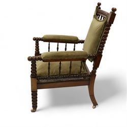 Late Victorian walnut bobbin turned armchair, curved cresting rail with bead moulding over turned spindle back, upholstered arms on turned balustrade supports, cane work seat over seat rail with matching bead moulding, loose seat cushion upholstered in olive green fabric, on tapering bobbin turned front supports with brass and ceramic castors, 