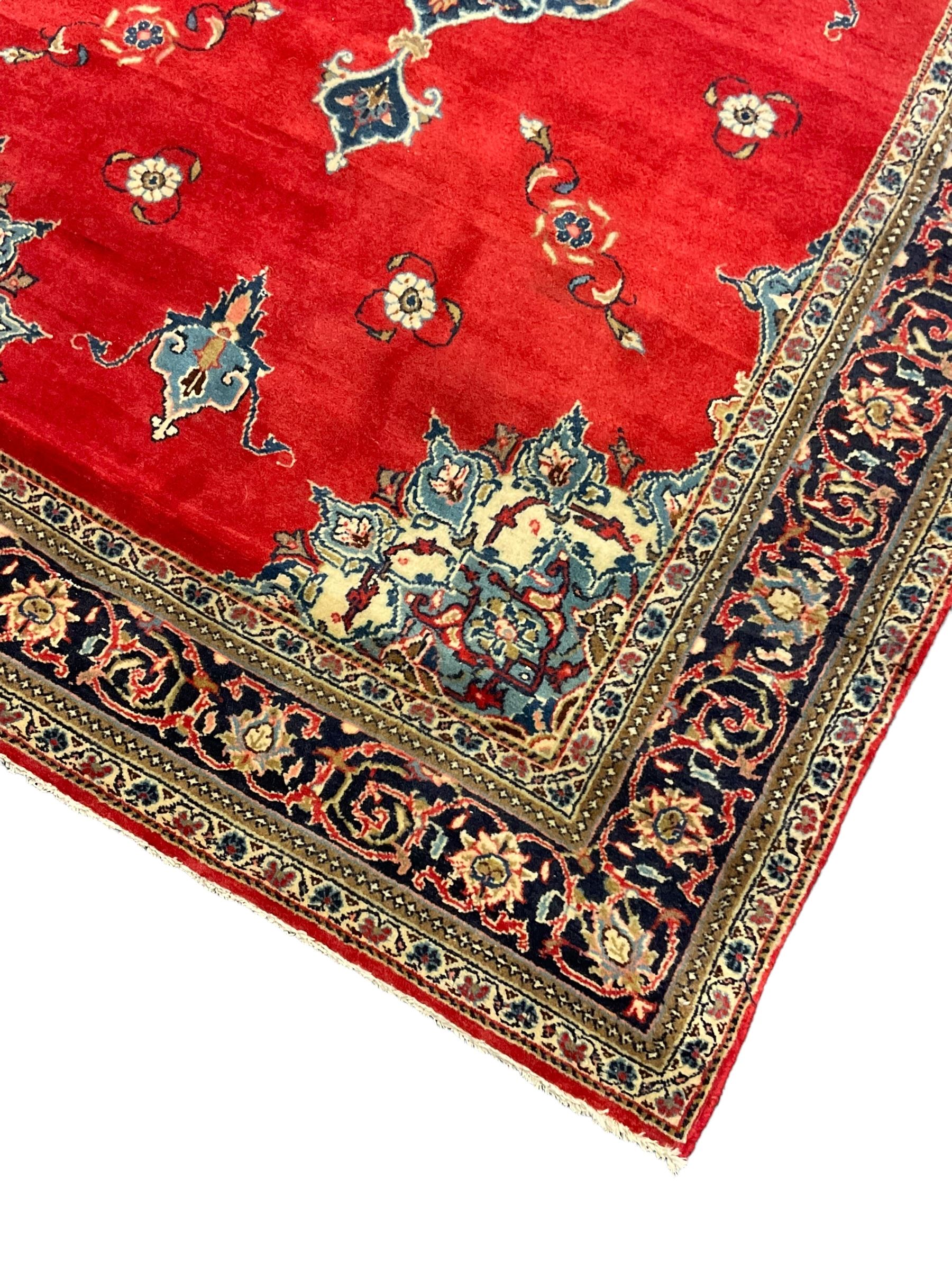 Persian Kashan crimson ground rug, the field decorated with interlacing medallion, floral design spandrels, guarded border with scrolling design decorated with stylised plant motifs