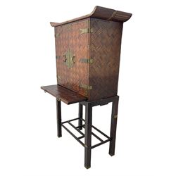 Chinese design bamboo and wood altar cabinet on stand, parquetry lattice-work bamboo, two doors with engraved metal fixtures enclosing drawers and shelf, fitted with slide, the stand pm square supports joined by a series of geometric stretchers