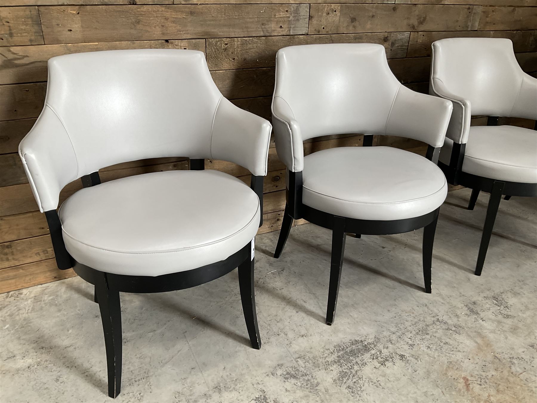 Four ebonised framed tub shaped armchairs, upholstered in grey fabric