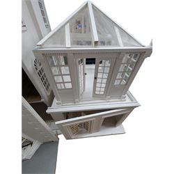 Large three storey modern dolls house, painted white with latticed windows, grey roof and metal fencing, with decorated interior, together with two dolls house garden rooms and two conservatories