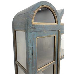 Tall painted glazed display cabinet, double arched top over two glazed doors, fitted with three shelves, in rustic blue paint finish, on cabriole feet