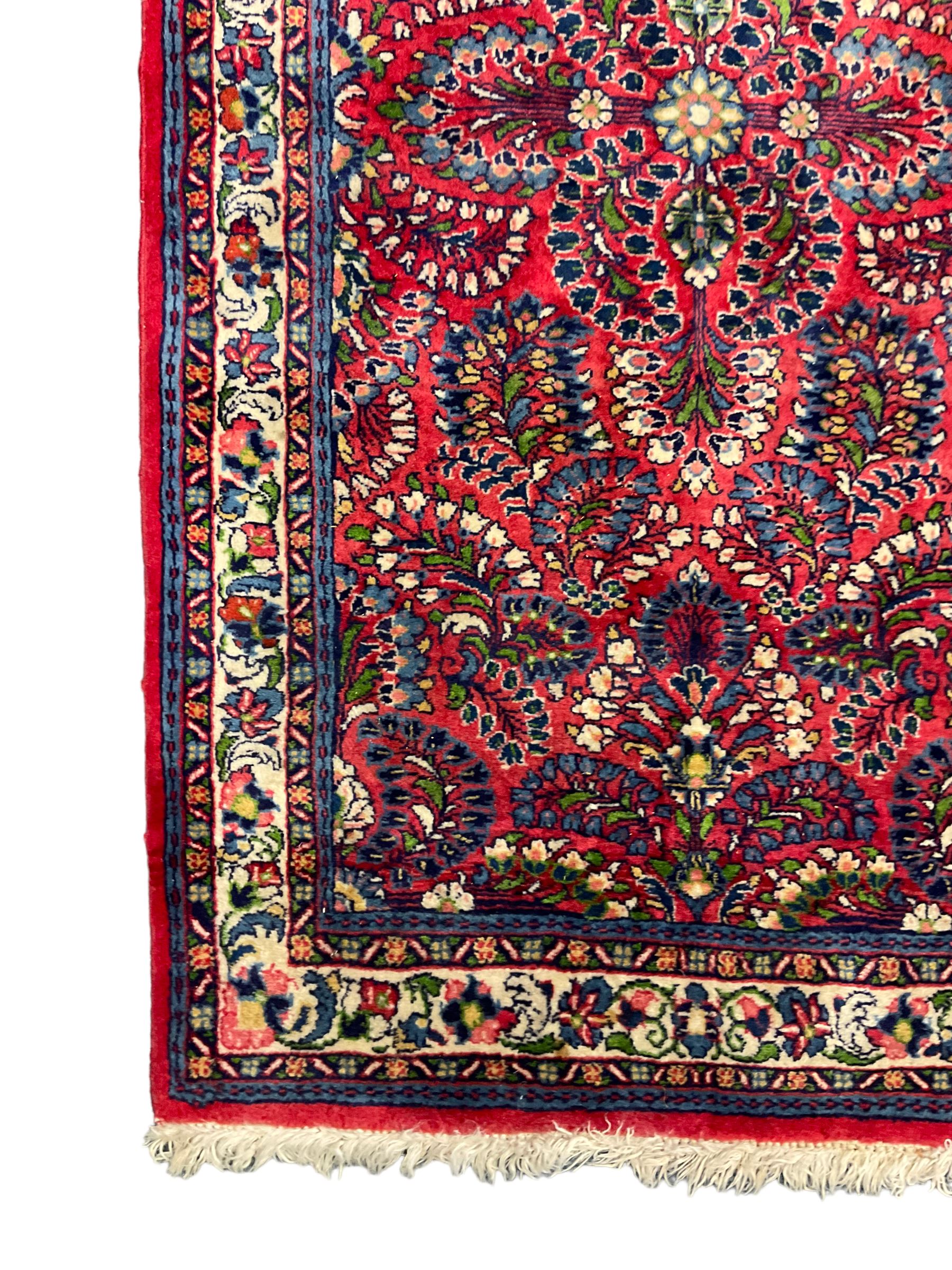 Small Persian red ground rug, the field decorated with an overall floral design, guarded ivory ground border decorated with trailing flower heads and foliage