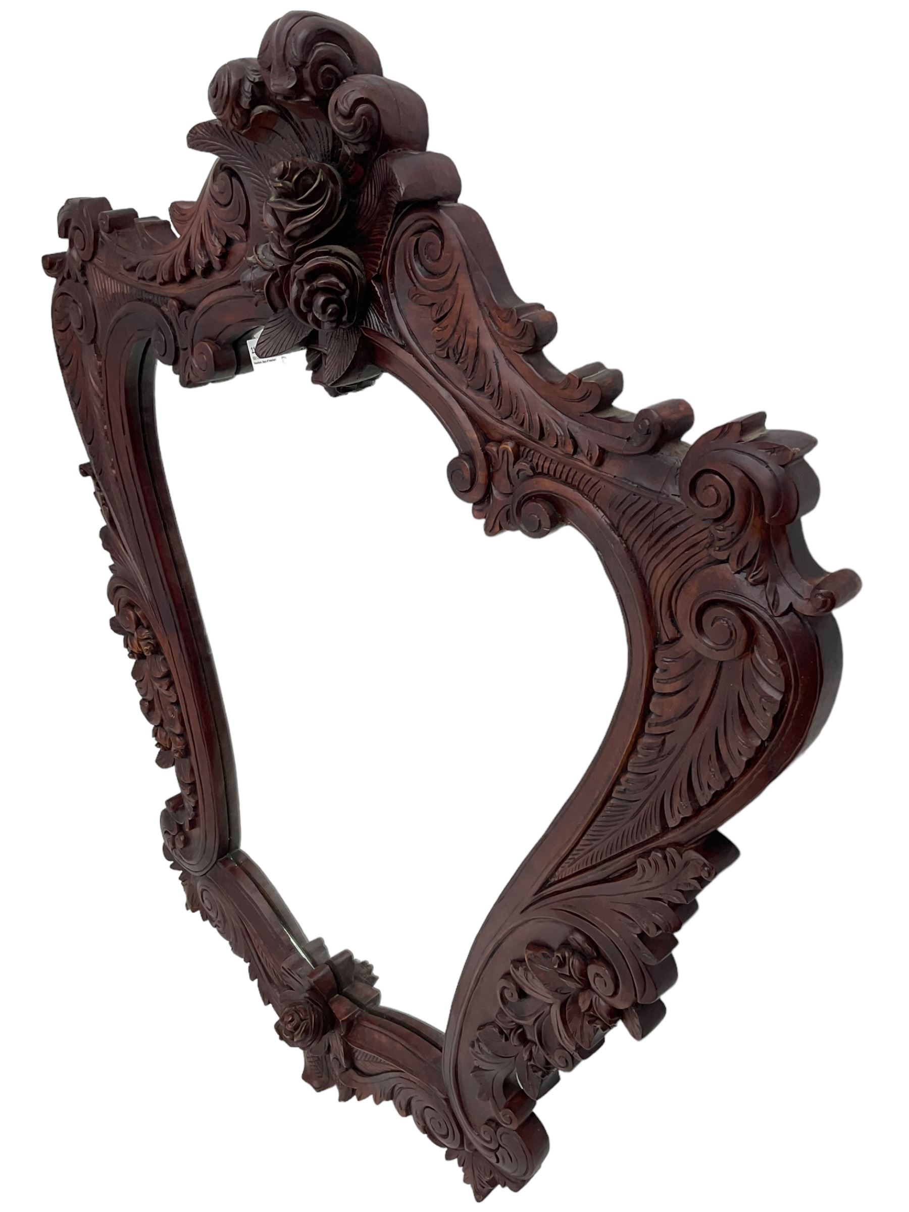 Large carved hardwood wall mirror, shaped floral carved pediment over trailing and scrolled foliage decoration, plain mirror plate 