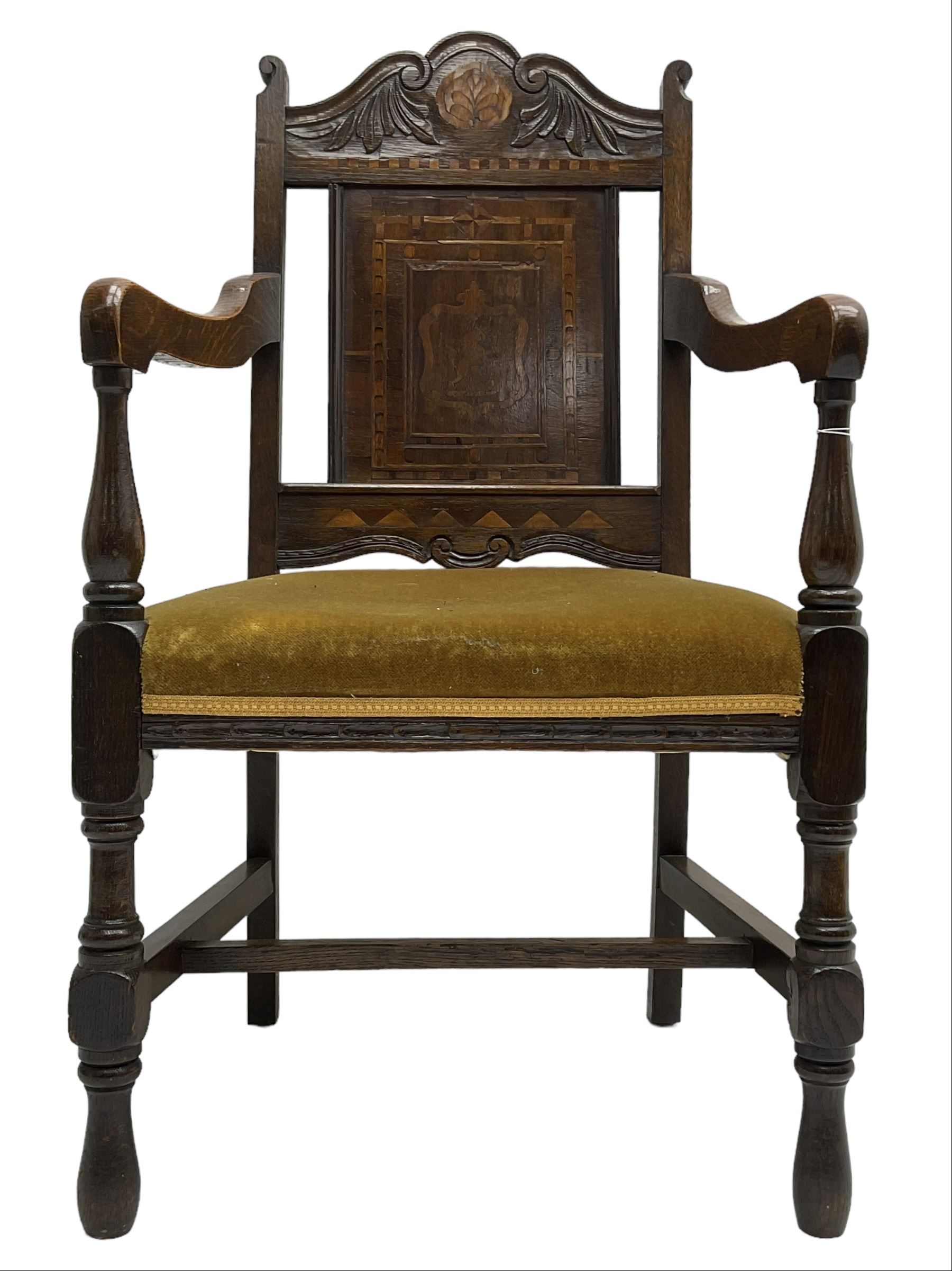 Late 19th to early 20th century oak elbow chair, the shaped cresting rail carved with scrolls and foliage, panelled back inlaid with parquetry work and central rampant lion within shield, upholstered seat, on turned supports joined by H stretchers