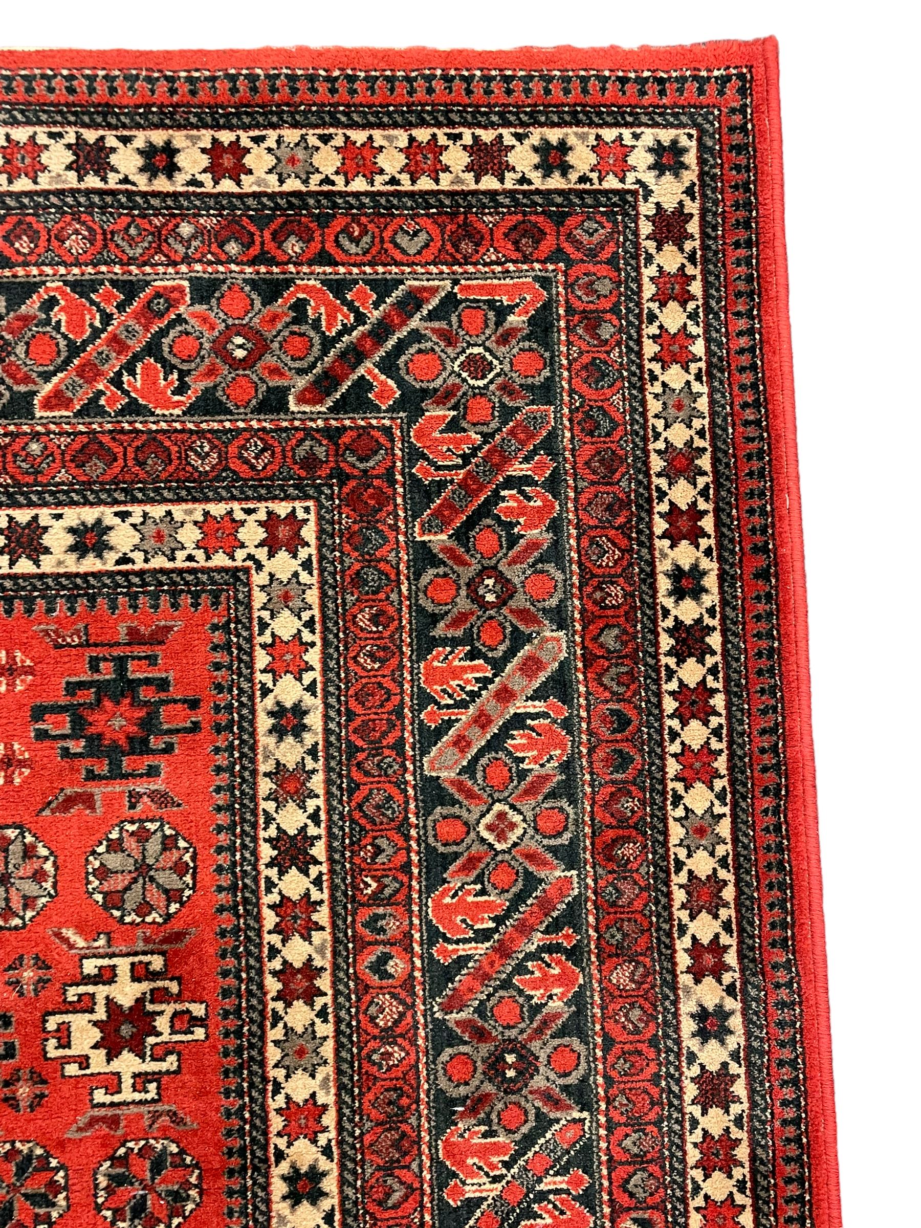 Persian design red ground rug, the field decorated with geometric motifs, repeating multiple band border 